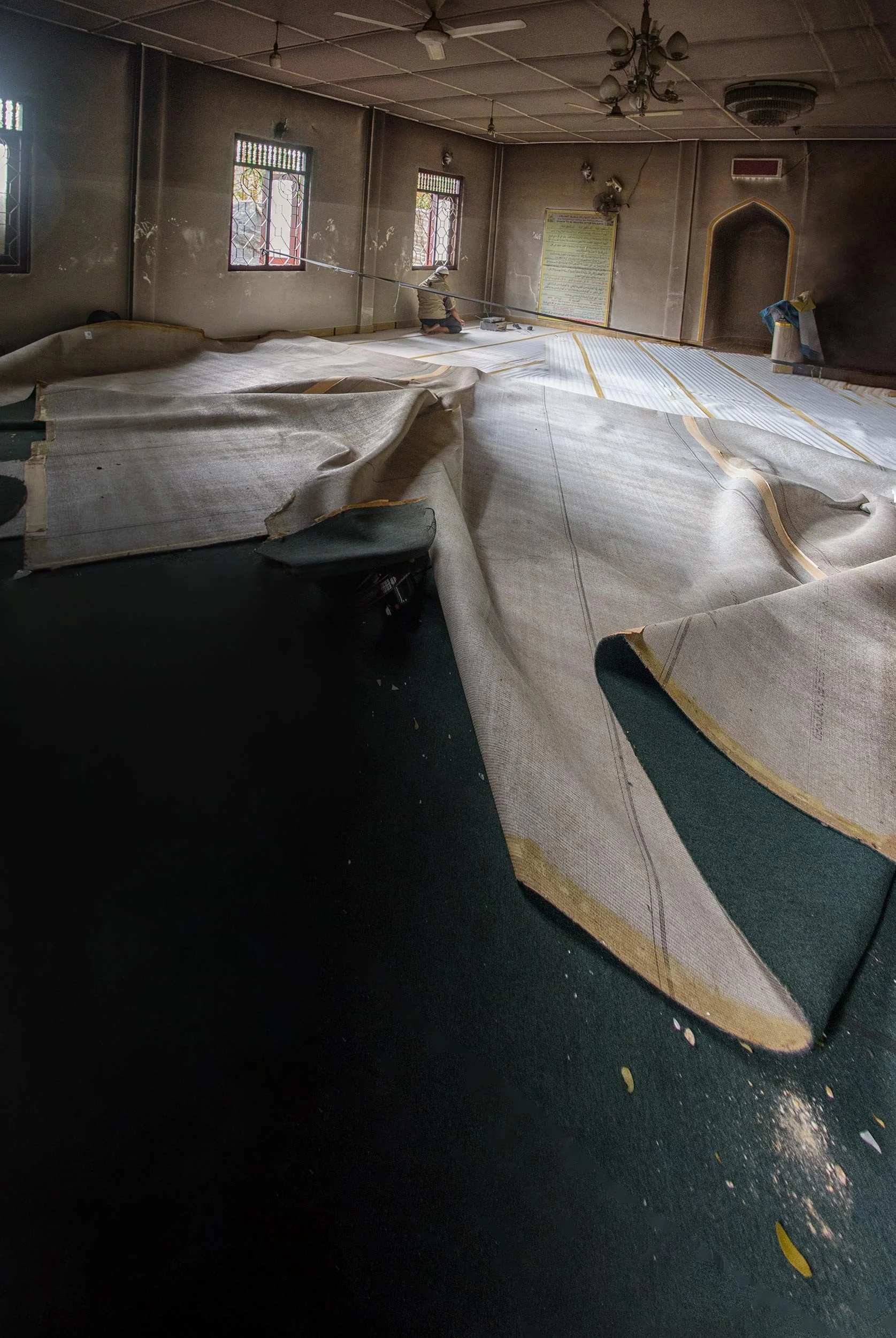 inside a damaged mosque, the carpet is lifted and reset as the space is slowly made usable again.  The Noor Jummah Mosque in Digana was among the religious sites affected during the March 2018 violence in the Kandy District. The mosque and surroundin