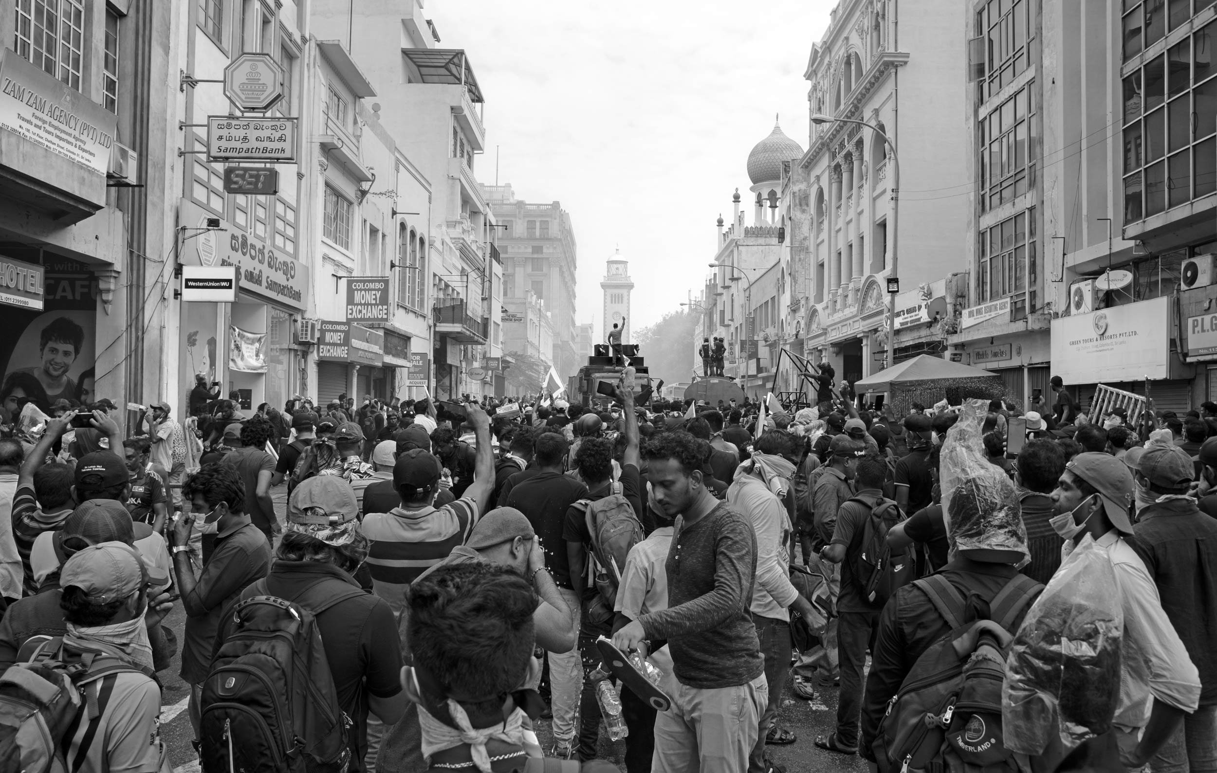 A crowd gathers in the smoke and pressure of Colombo, where private frustration became collective refusal.