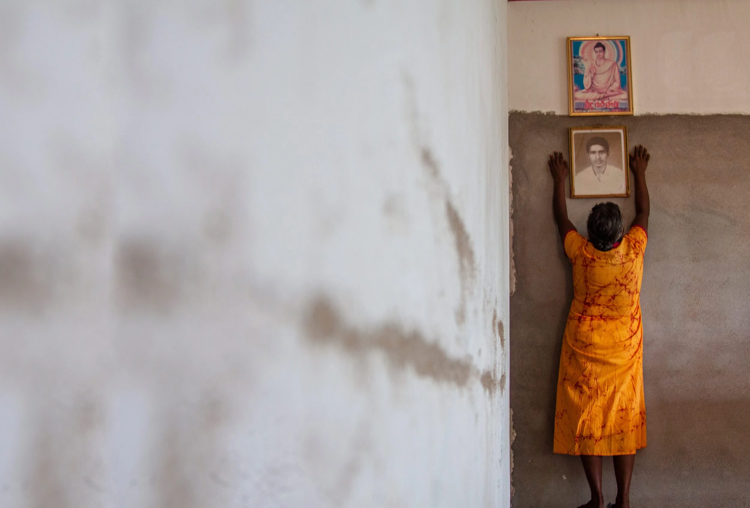 In her home in Rathgama, a mother places the photograph of her disappeared son beneath an image of the Buddha. More than three decades have passed since he was taken away, yet his absence remains present in every corner of the house. The fading portr