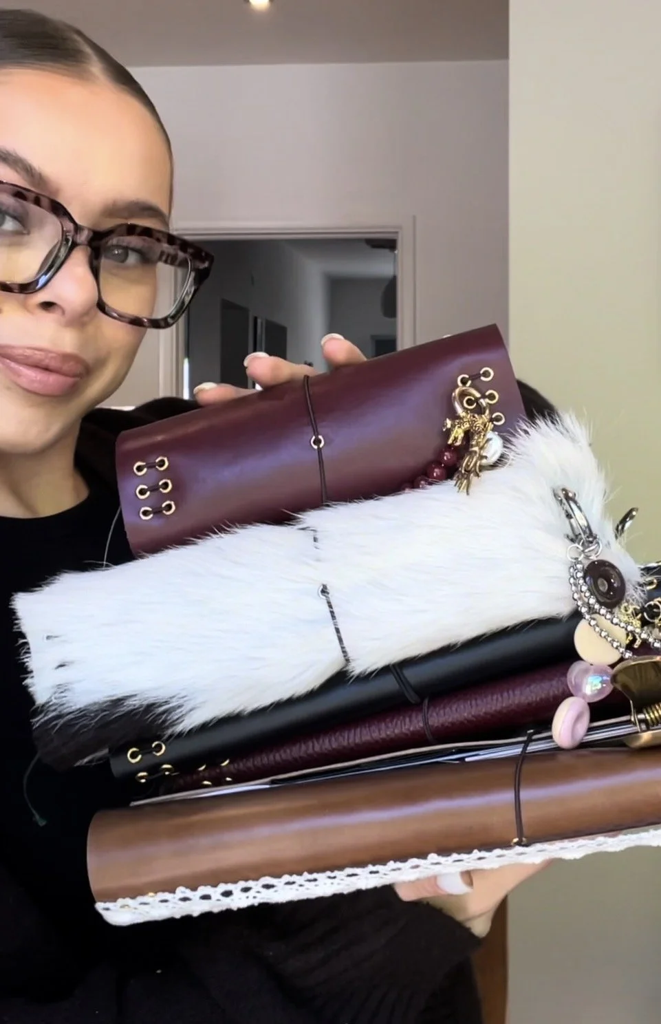 A woman holding a stack of various handbags and accessories.
