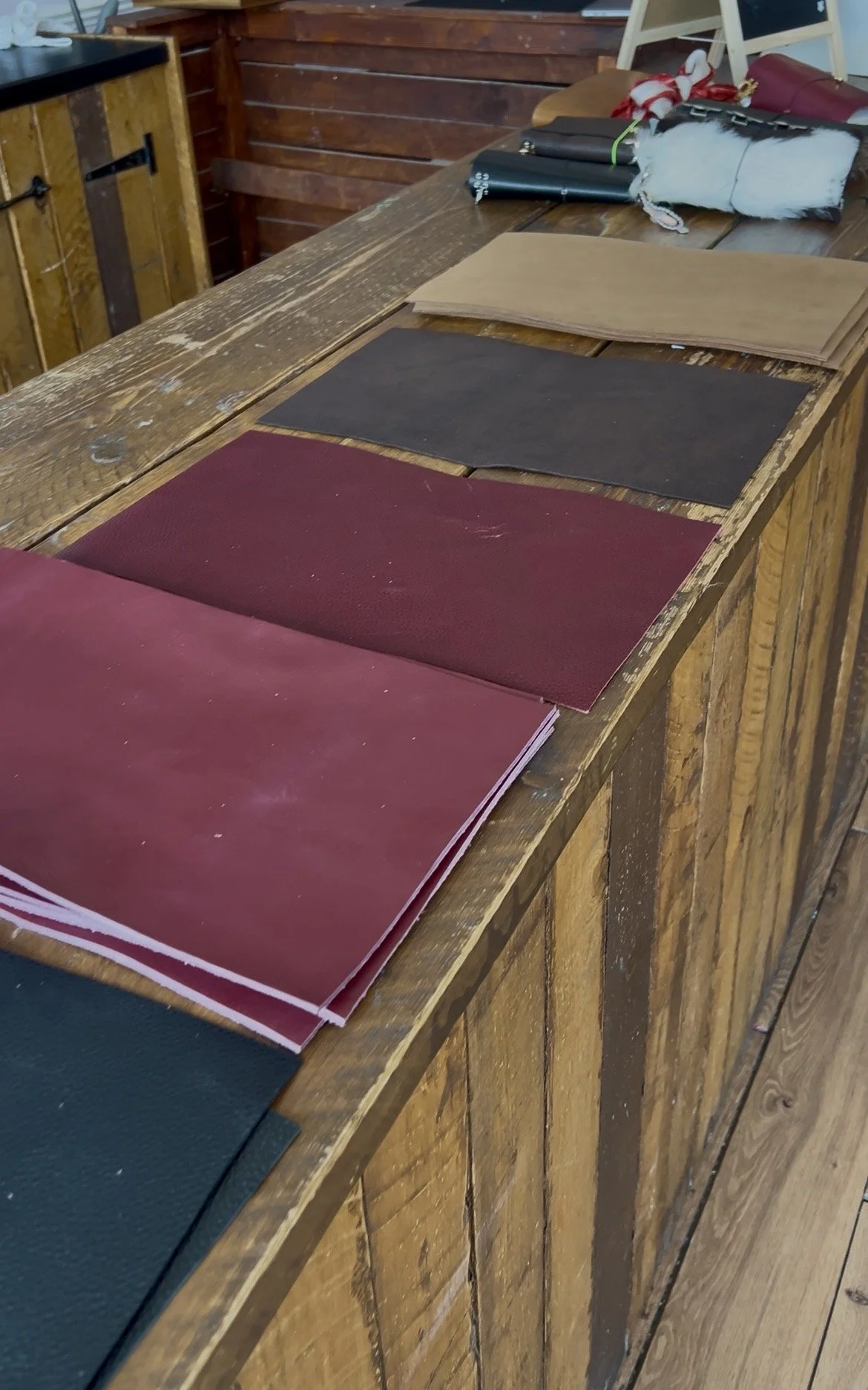 Samples of different colored fabric or paper swatches laid on a wooden counter with assorted objects in the background.