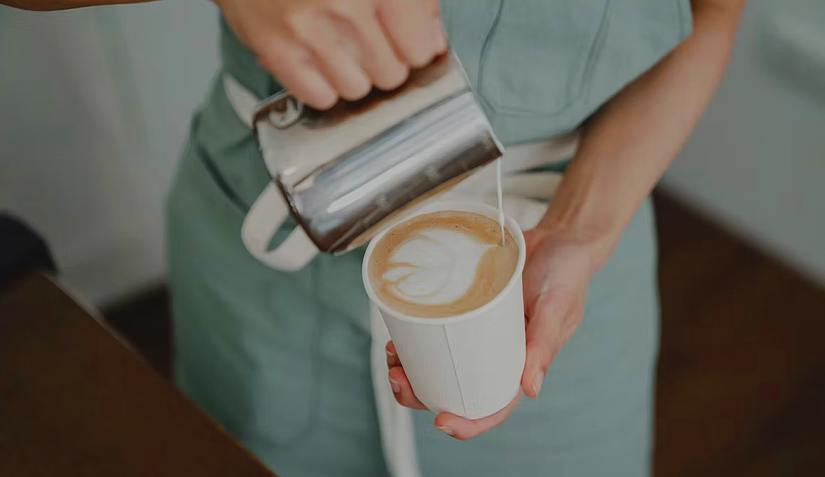 Barista pouring steamed milk into a handcrafted latte at Kaffee Klatsch coffee shop in Dayton, Virginia.