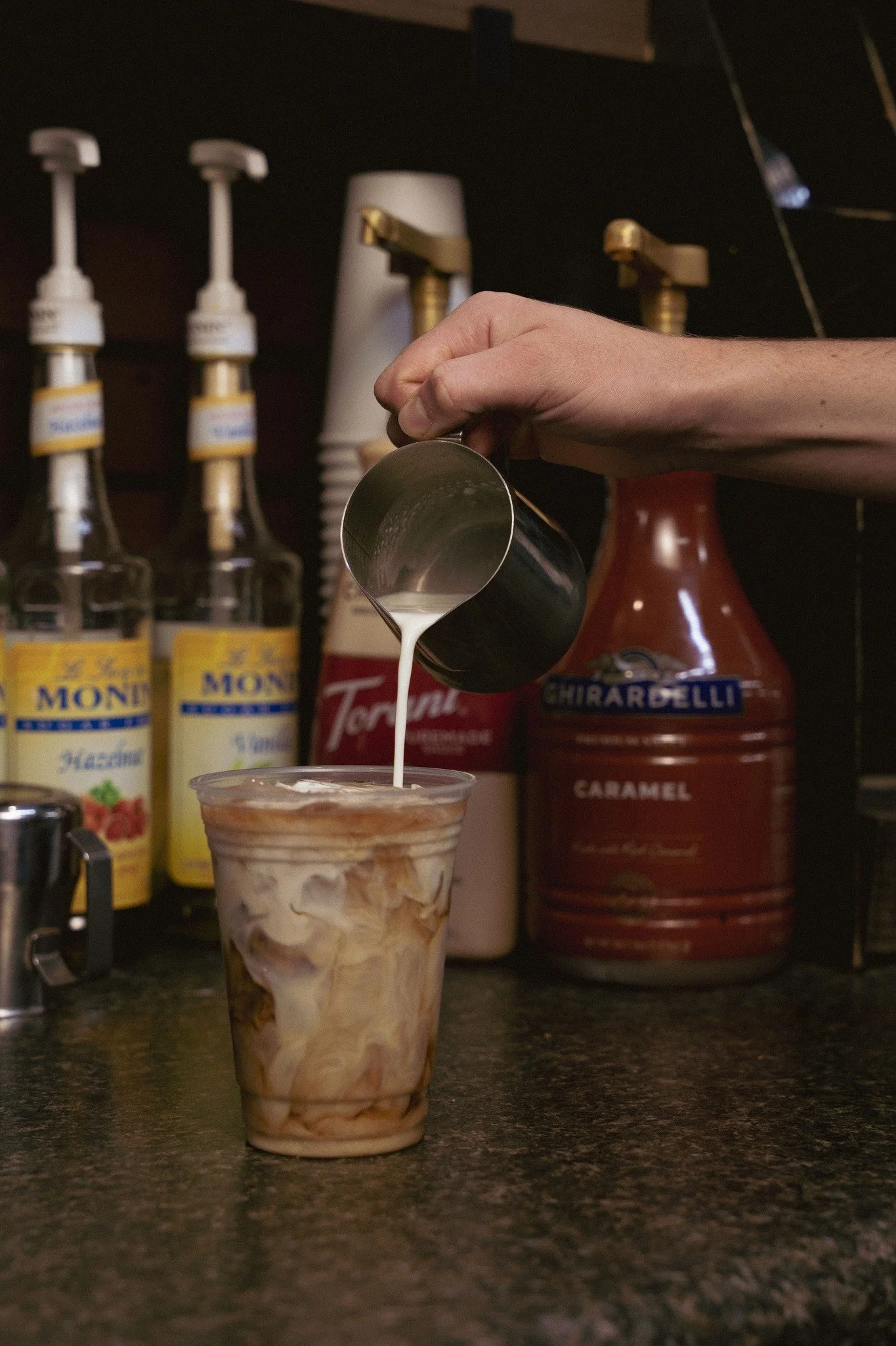 Iced coffee drink with milk pouring in and syrup options in Dayton Virginia