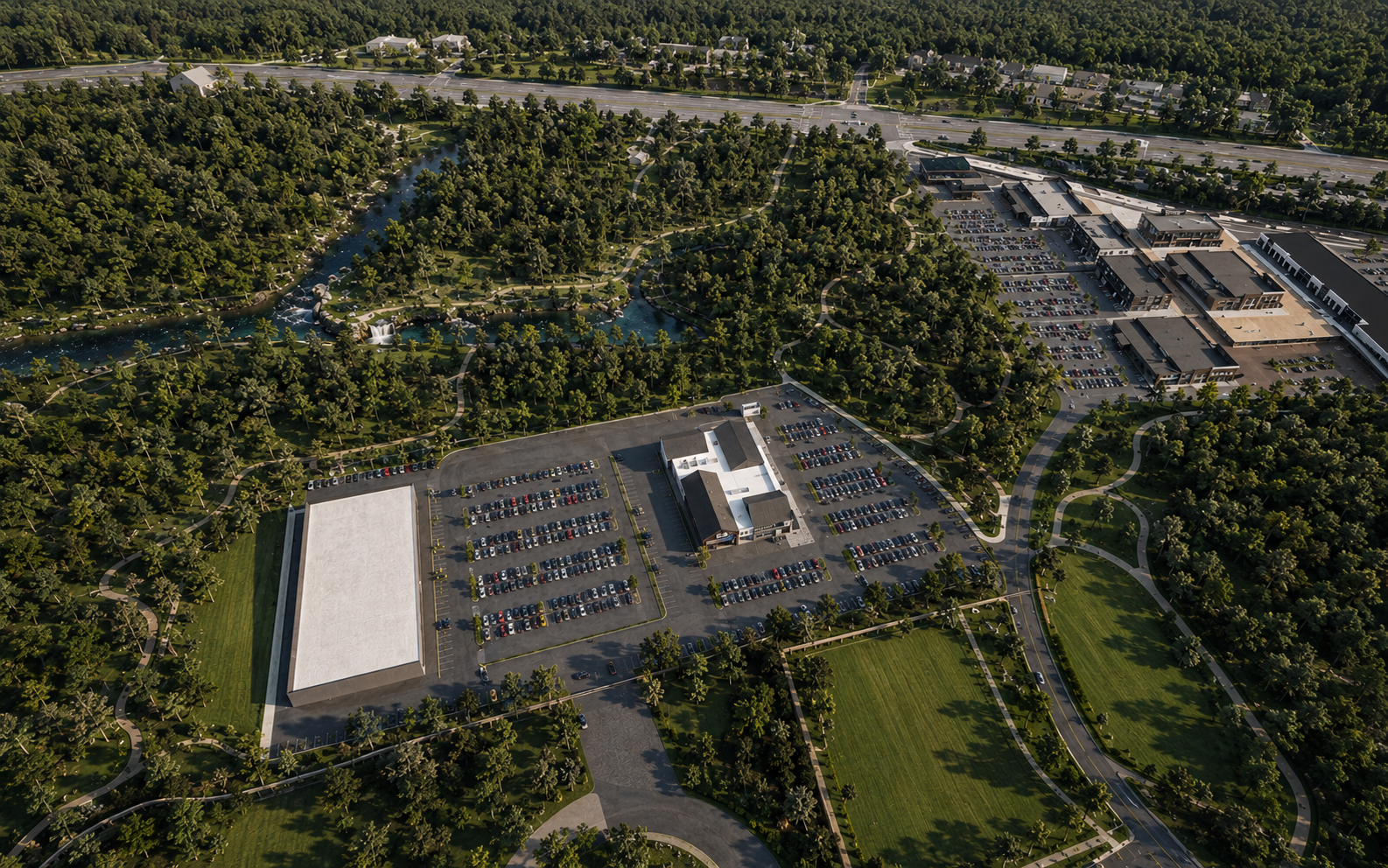 Aerial view of a park with a pond and walking paths, surrounded by trees, parking lots, and a shopping center in the distance.