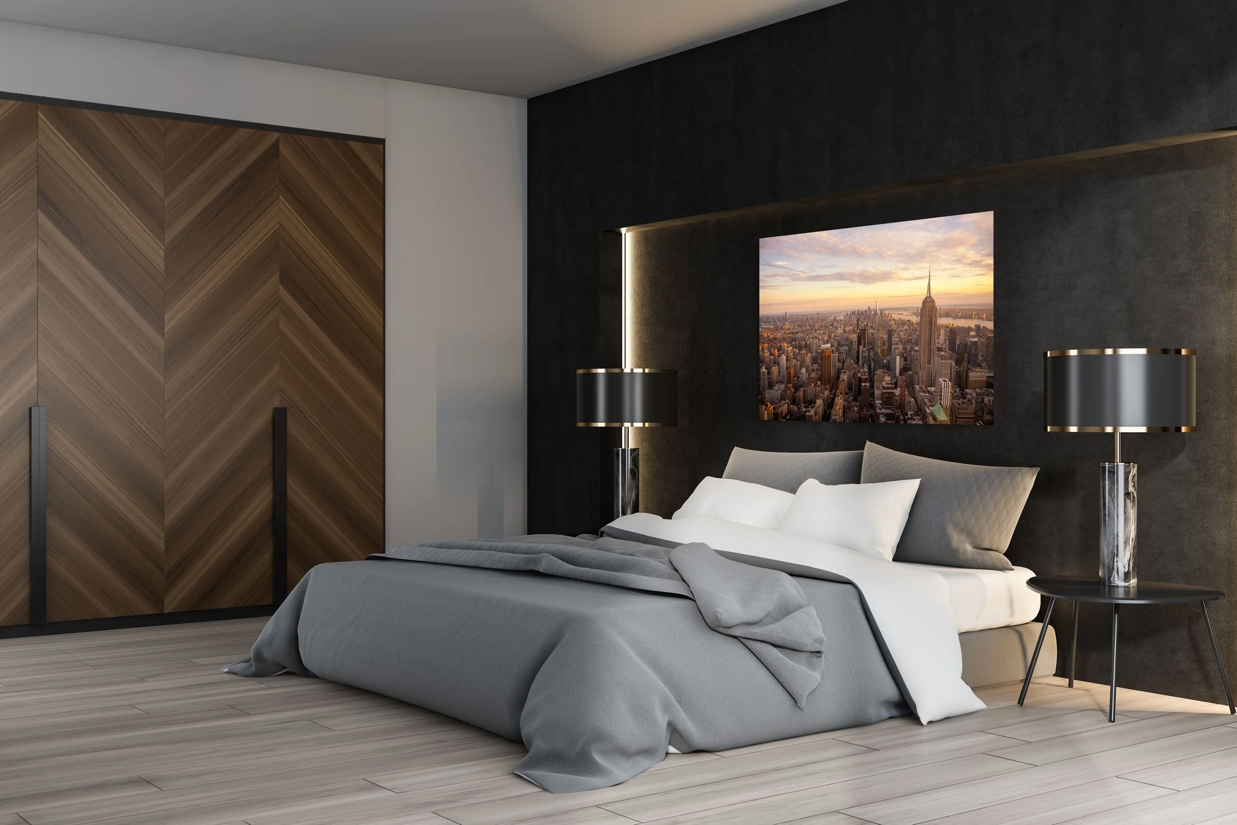 Modern bedroom with a gray bedspread, white pillows, and a cityscape artwork of New York City including the Empire State Building on the wall. Black and gold lamps are on bedside tables, and a wooden closet with chevron pattern doors is on the left.