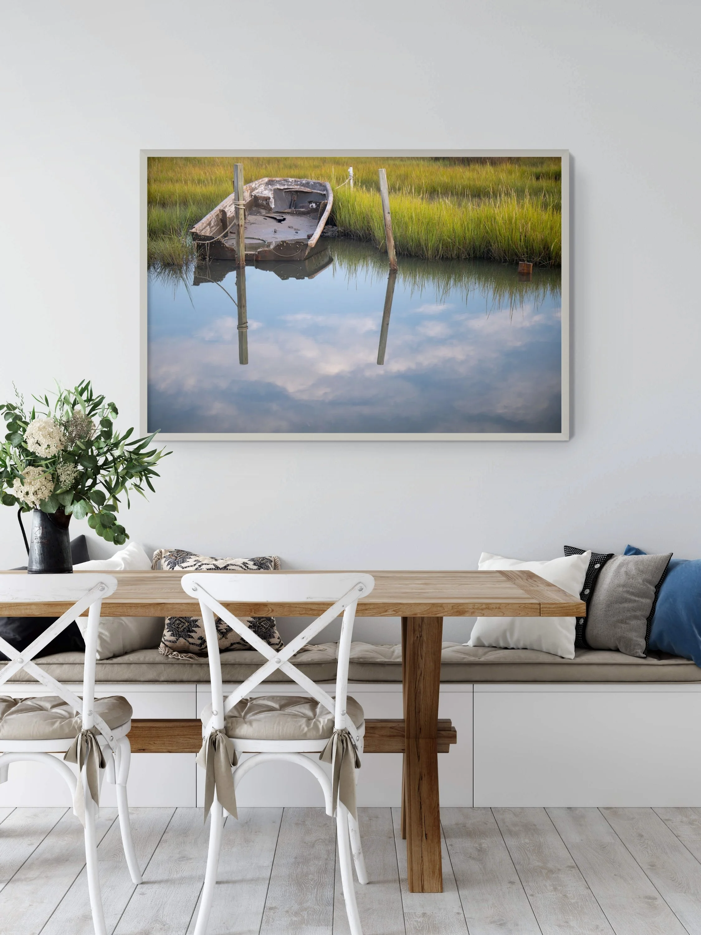 Painting of an abandoned boat in marshland with green grass and calm water reflecting the sky and reeds.