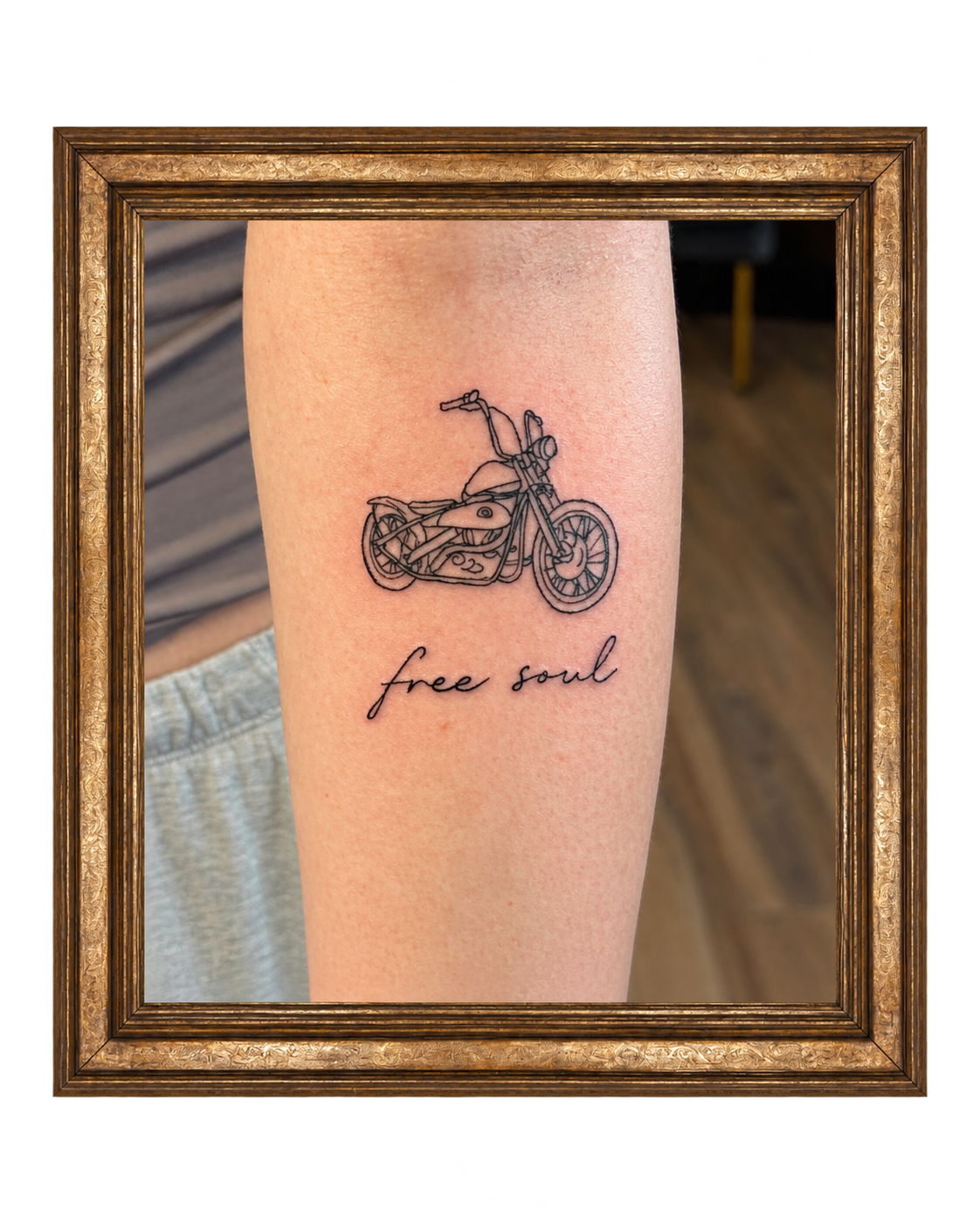 Tattoo of a motorcycle with the words 'free soul' in cursive below it on a person's arm.