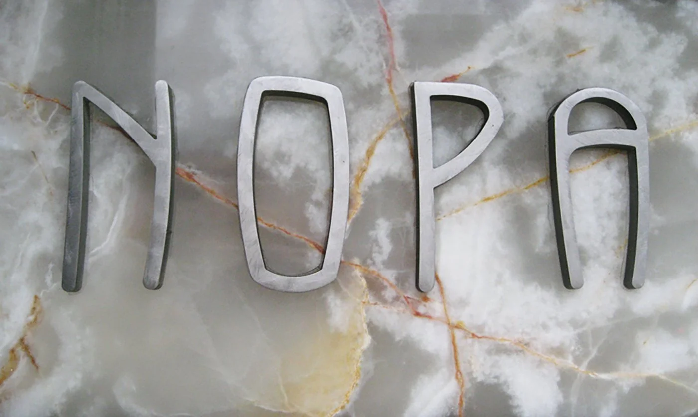 Metal letters spelling 'YODO' on a marble wall.