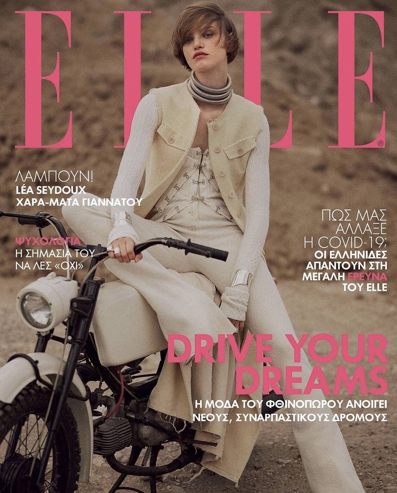 Elle magazine cover featuring a woman sitting on a motorcycle, wearing a beige vest and cream-colored outfit, with large pink text and Greek headlines.