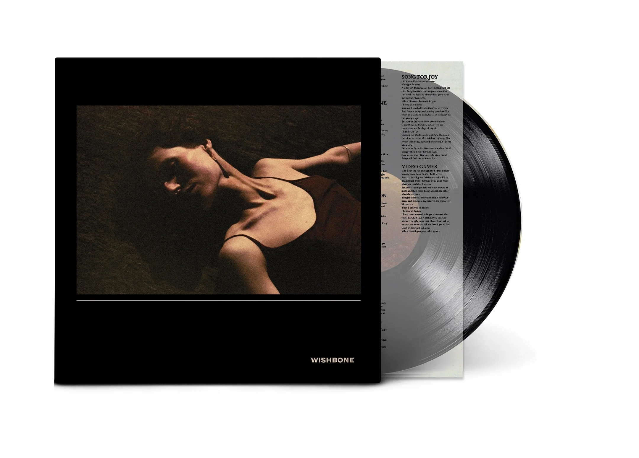 A vinyl record and album cover with a woman lying on the ground, wearing a black dress, and with long dark hair. The album cover has the word 'WISHBONE' at the bottom.