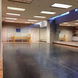Empty airport baggage claim area with yellow barriers and a white counter.