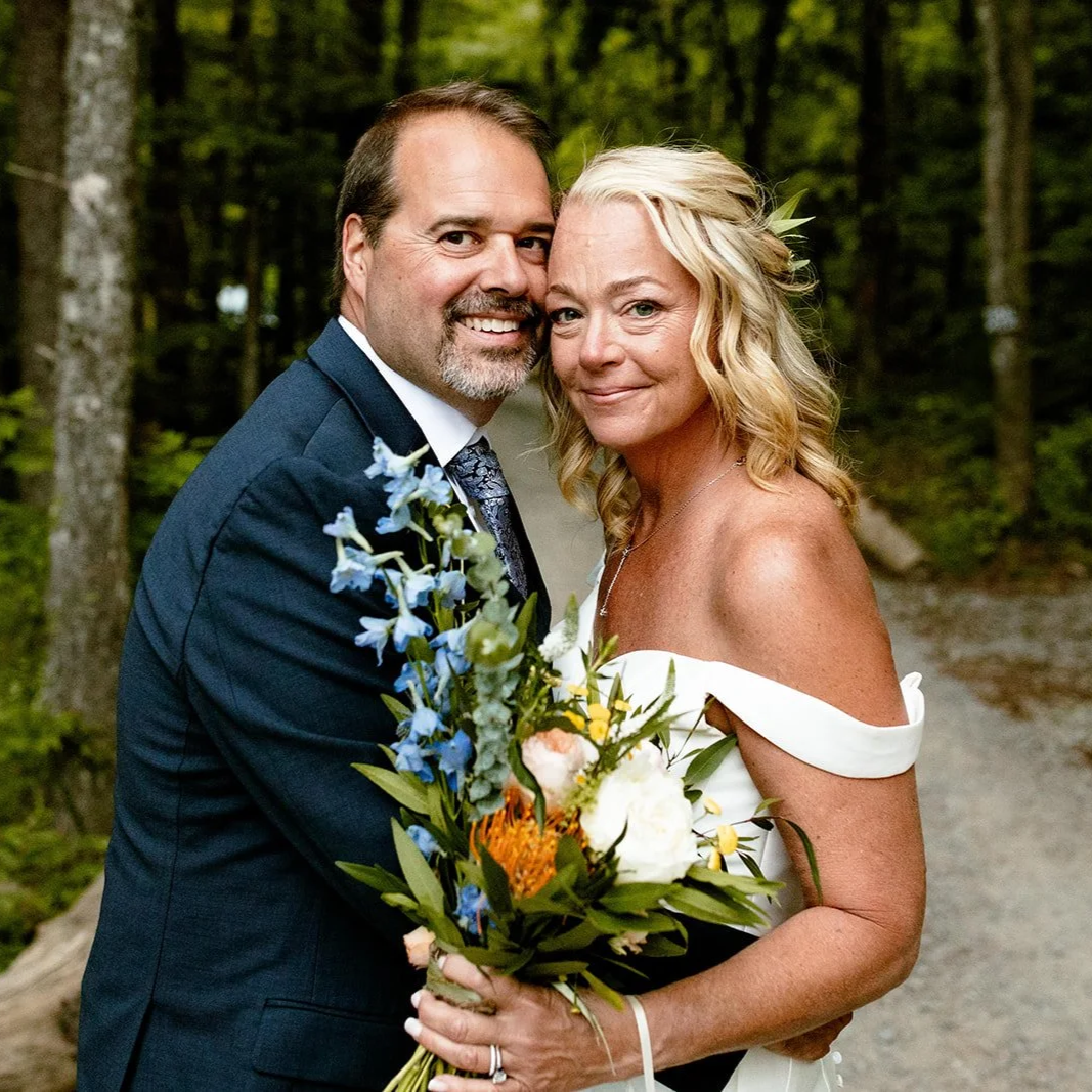 Laurie’s customers, Mariana and Carmen holding hands on a green lawn on their wedding day.