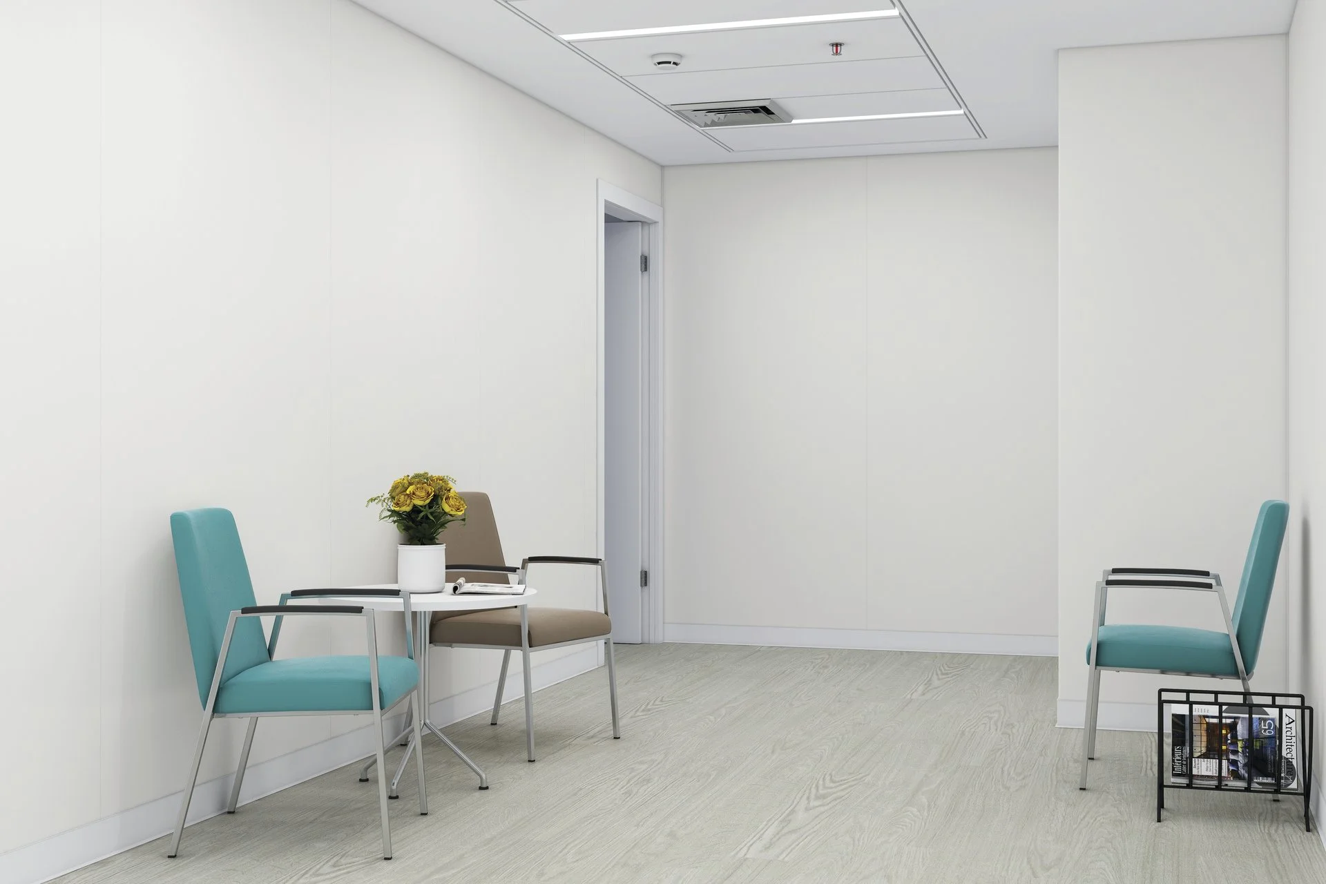 A waiting room with white walls and light-colored flooring, furnished with teal and beige chairs. A small round table holds a potted yellow flower, a magazine, and a pen. There is a door in the background and a black magazine rack near the right side