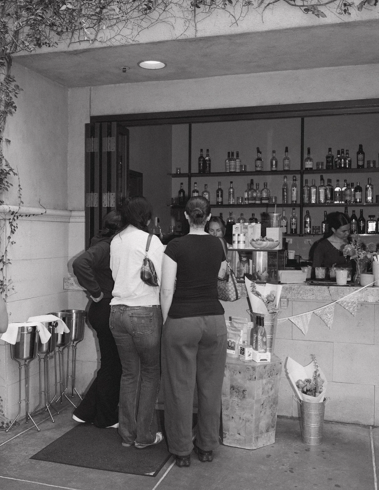 Customers ordering drinks at the Flora Cafe pop-up bar at Galletto Ristorante outdoor patio with merchandise and flowers displayed