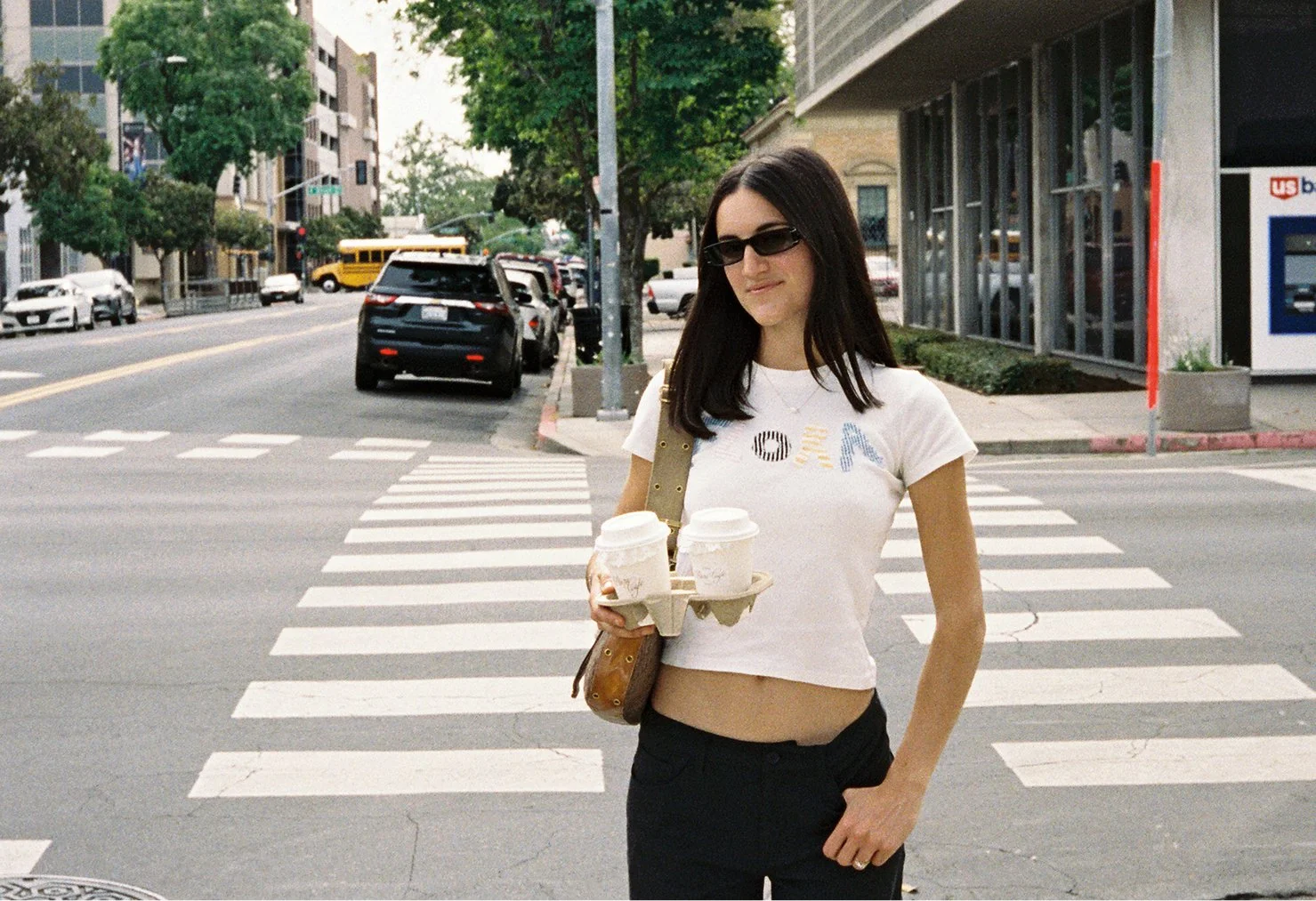 Hannah Culver founder of Flora Cafe holding a drink carrier with cups at a downtown Modesto street corner