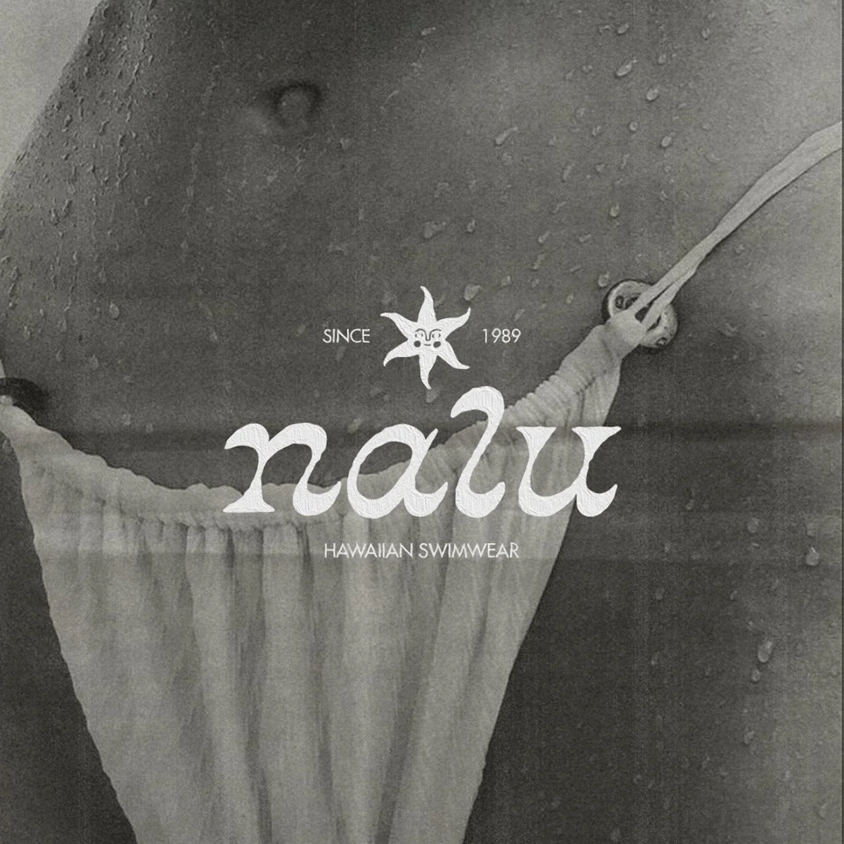 Close-up of a person wearing a swimsuit, water droplets on skin, holding onto a flotation device, with text overlay advertising 'Nau Hawaiian Swimwear' established in 1989.