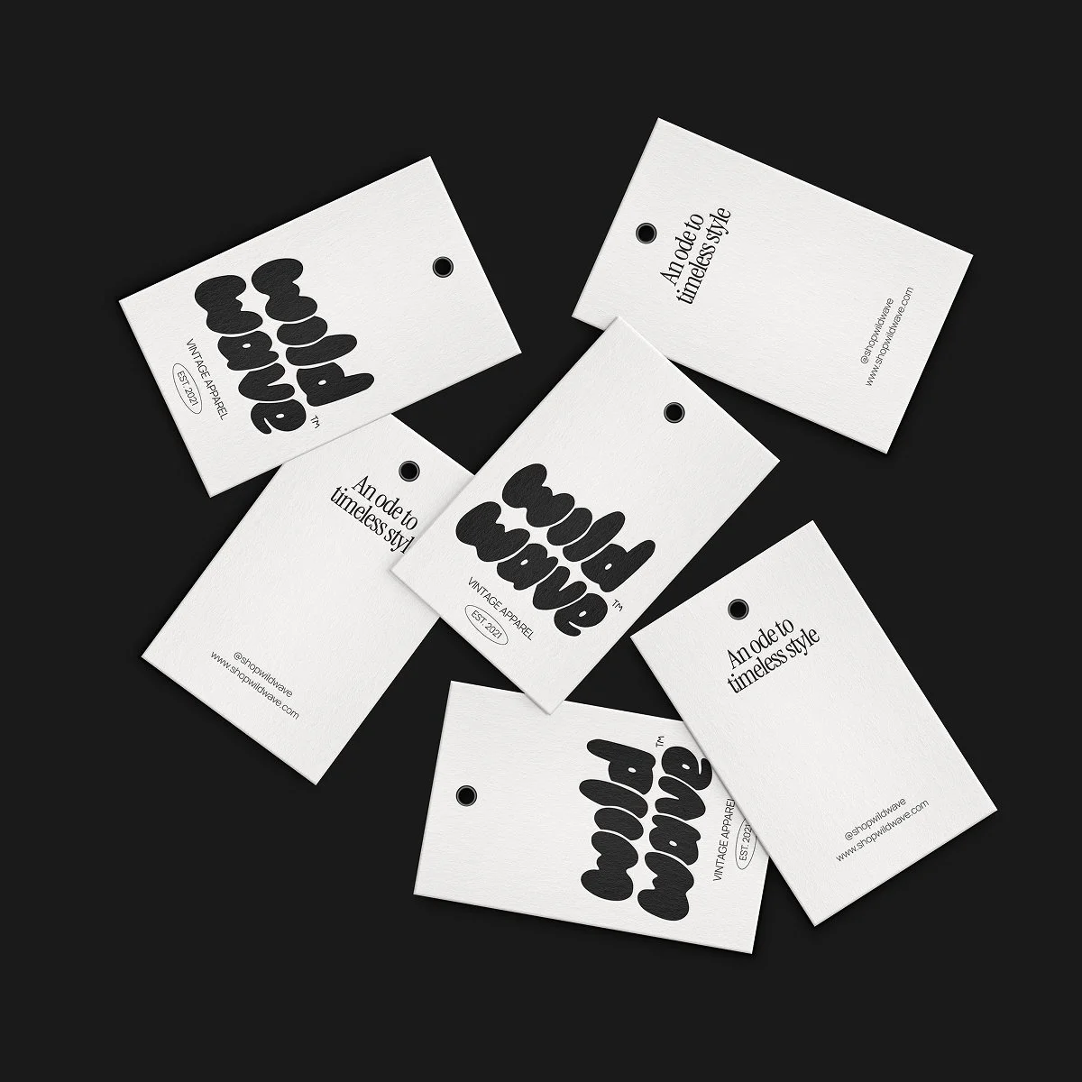 Collection of white clothing tags with black text and a circular hole at the top, arranged on a black background.
