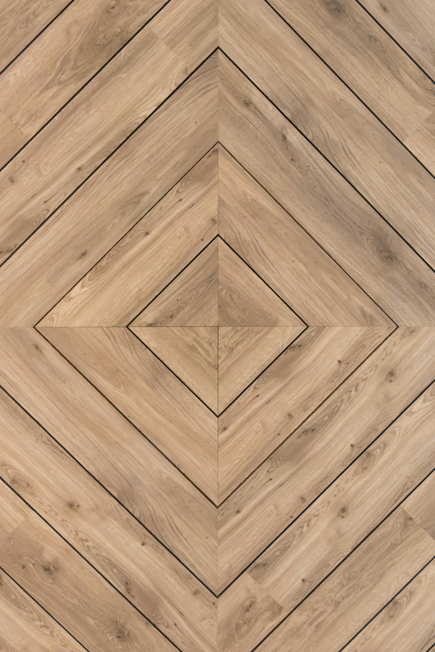 Wooden floor arranged in a herringbone pattern with a central diamond-shaped design.