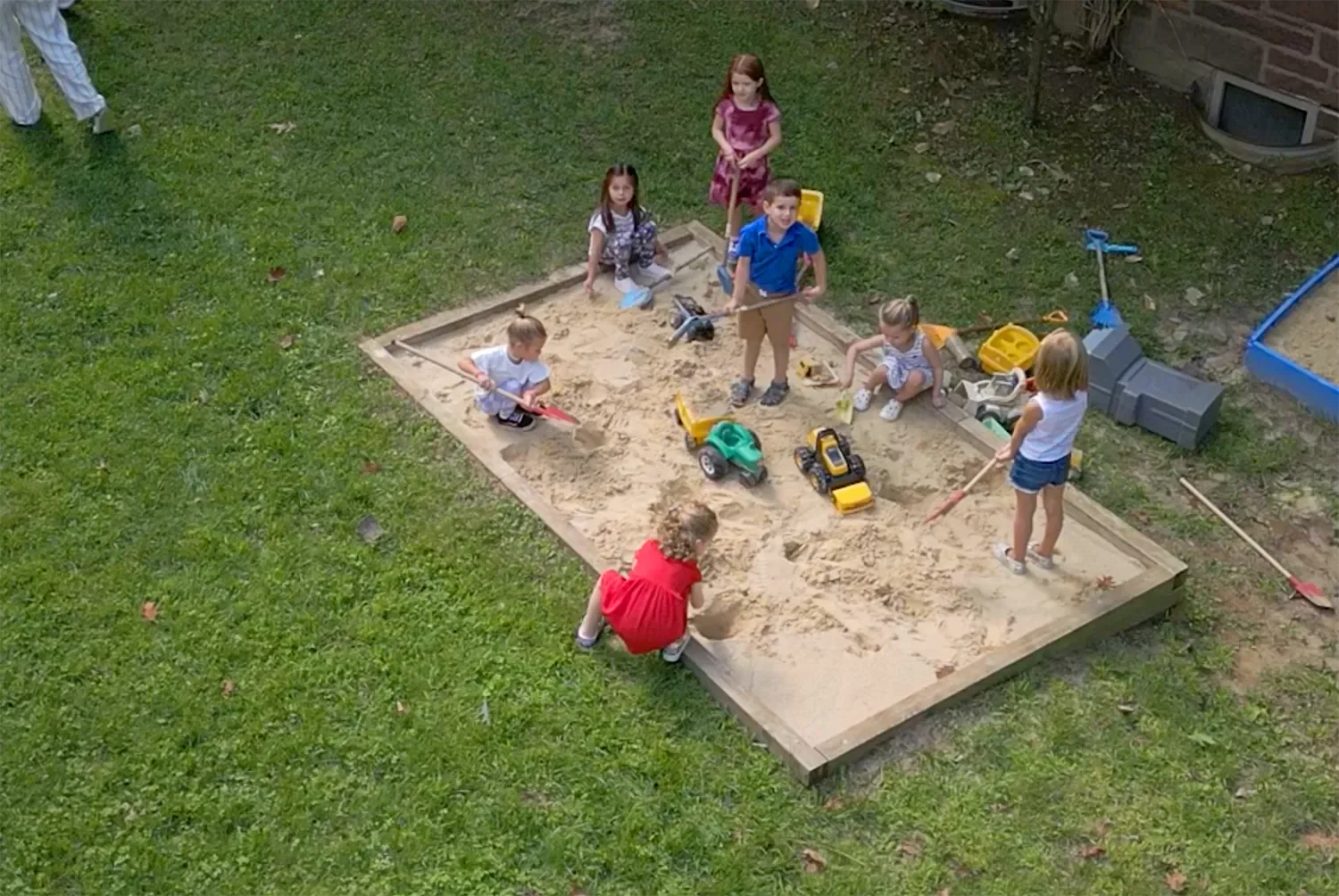 A group of children playing outside in a sandbox at St. Thomas’ Preschool.