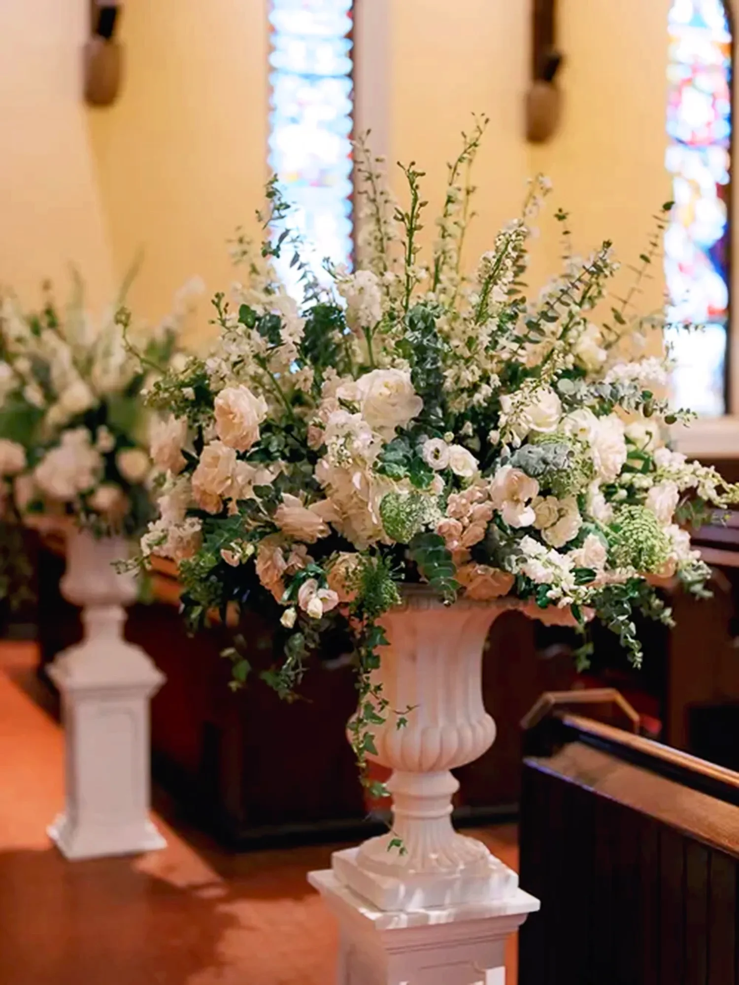 Two floral arrangements stand at the beginning of the aisle in the main church at St. Thomas’ Church Whitemarsh.