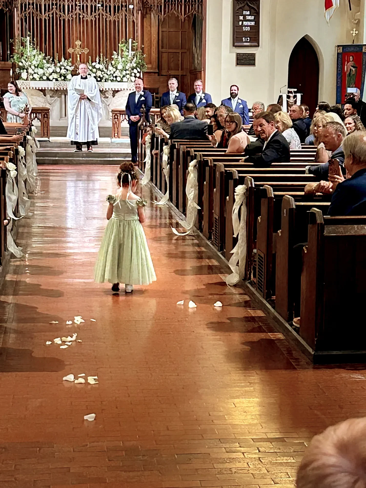 Flower girl dropping petals during wedding ceremony in main church at The Retreat at St. Thomas’ Church Whitemarsh.