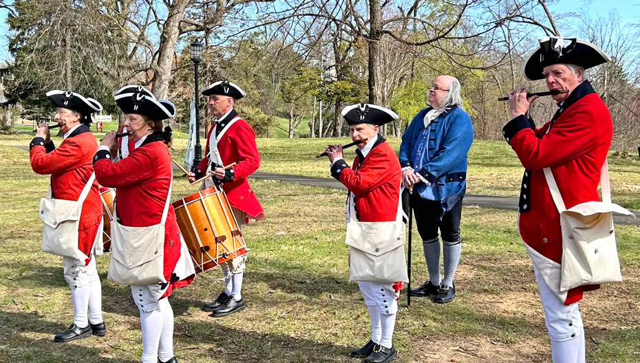 Colonial-era reenactors playing fifes and a drum outdoors with Benjamin Franklin at the Greater Whitemarsh 250th Collaborative Kickoff event for History Unleashed  at St. Thomas’ Church Whitemarsh.