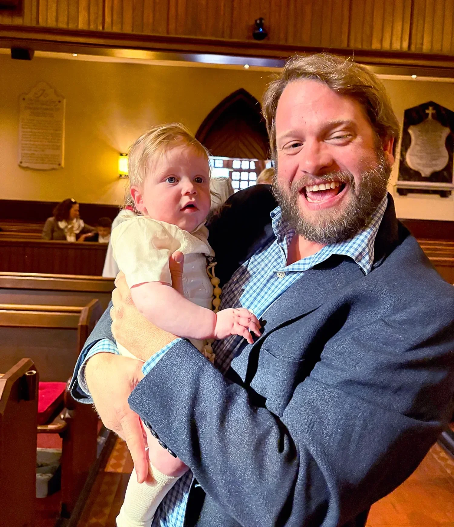 Father holding baby and smiling after baptism service at St. Thomas’ Church Whitemarsh.