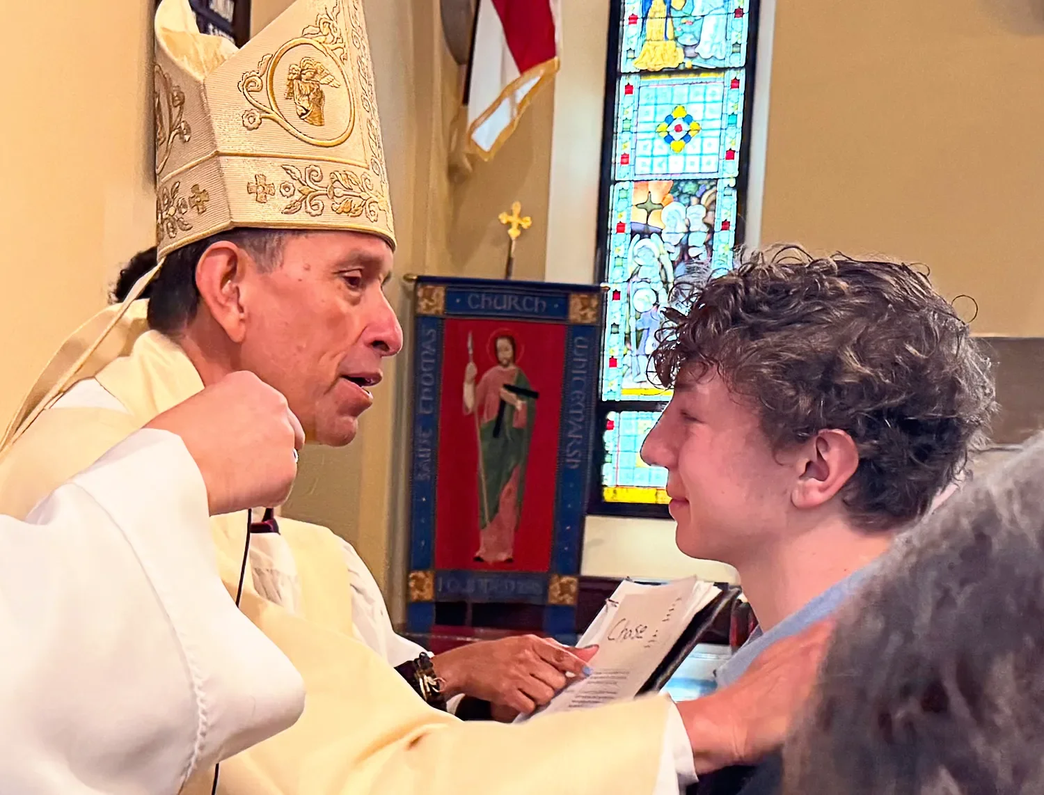 A bishop places a hand on a young person’s shoulder during confirmation at St. Thomas’ Church Whitemarsh.