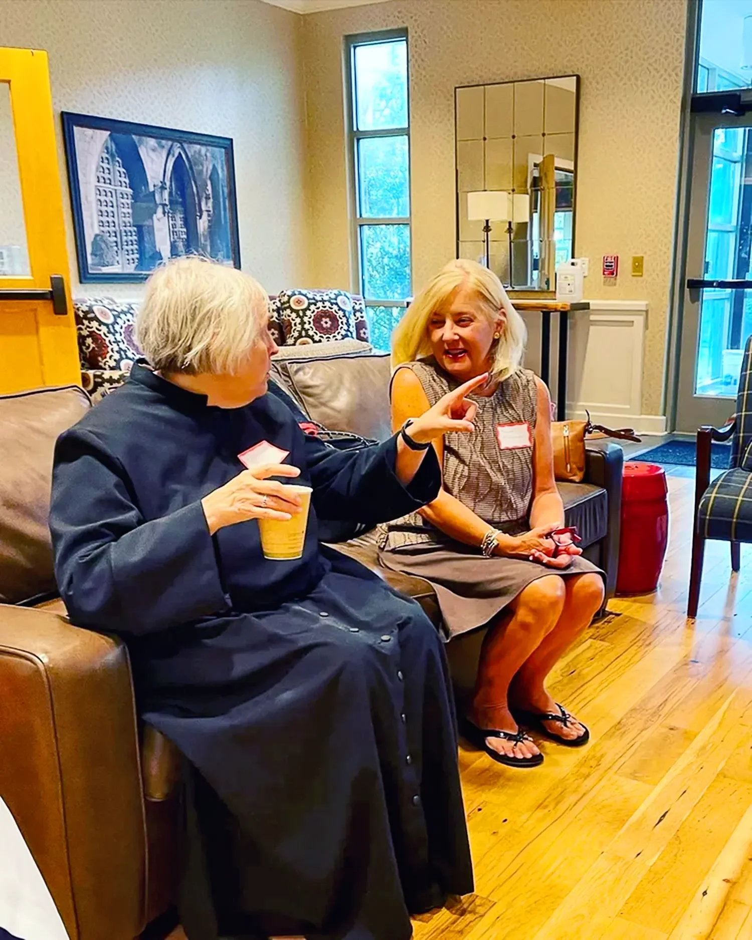 Two adults sitting and talking in a lounge space at St. Thomas’ Church Whitemarsh.