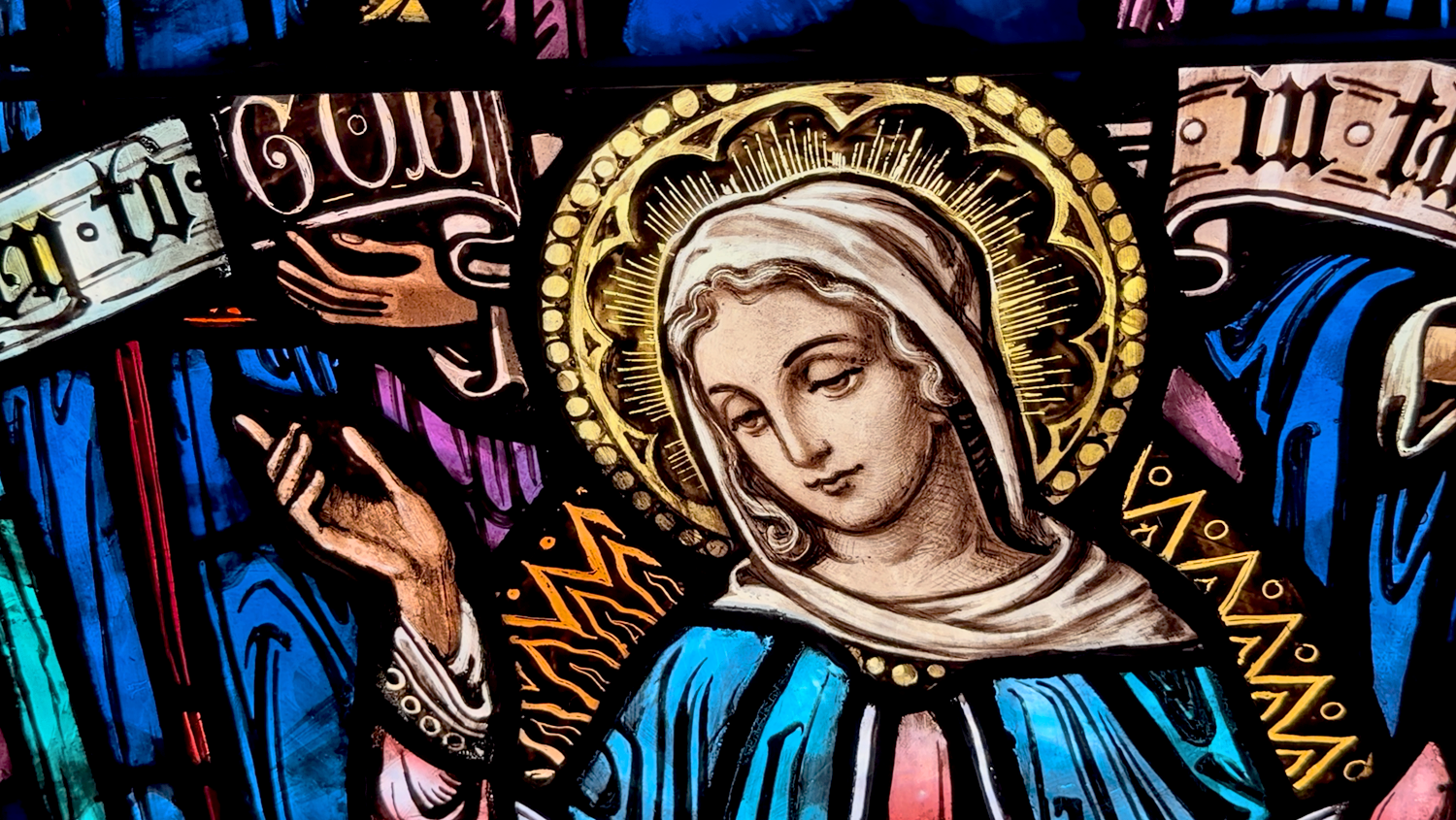 Closeup stained glass detail of Mary with her right hand raised inside the main church at St. Thomas’ Church Whitemarsh.