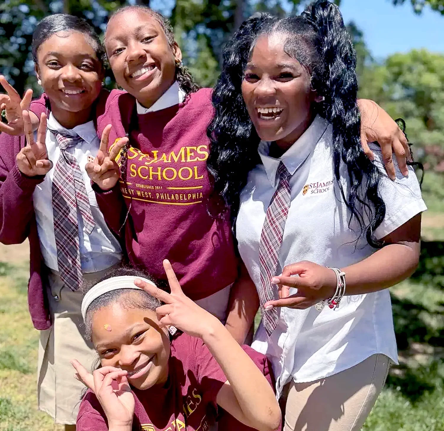 Four smiling students wearing St. James School uniforms.