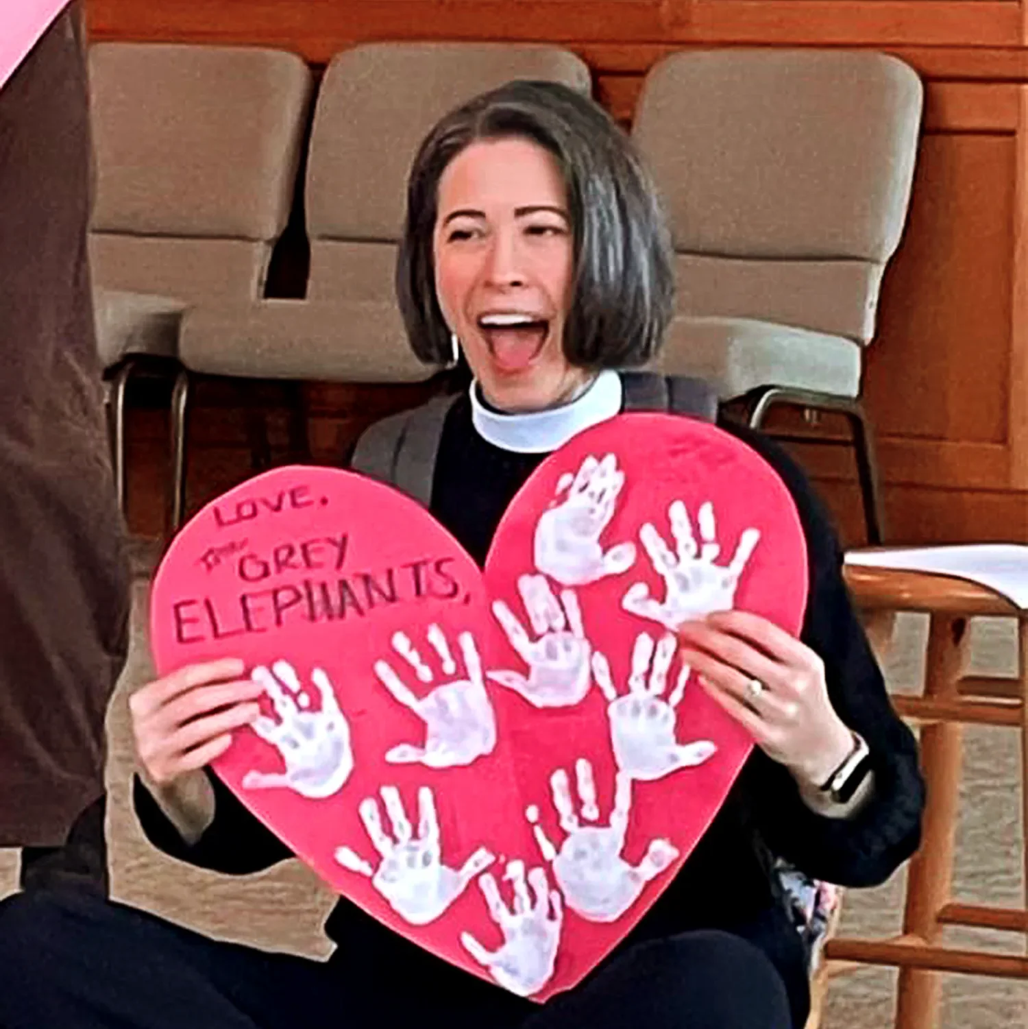 Mother Amy holding a large paper cutout heart with white handprints at St. Thomas’ Preschool.