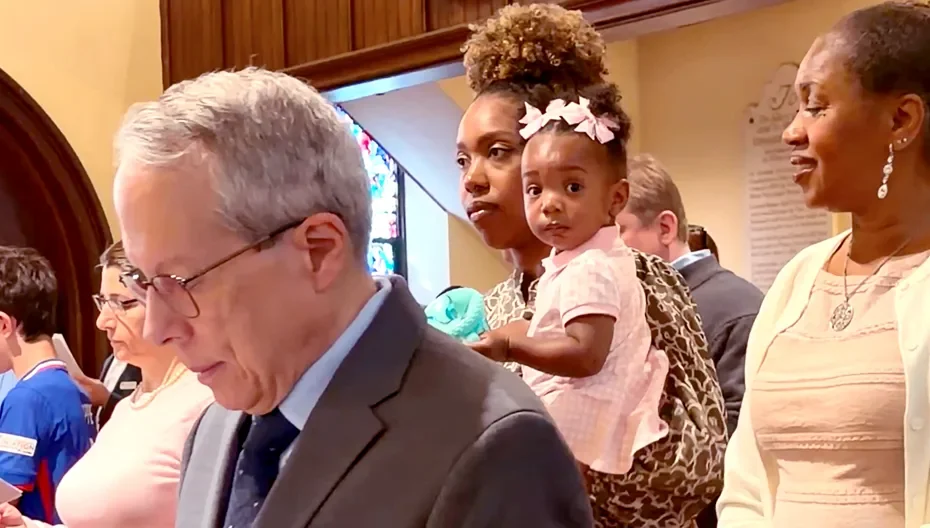 Congregants, including a family holding a young child, standing during a service at St. Thomas’ Church Whitemarsh.