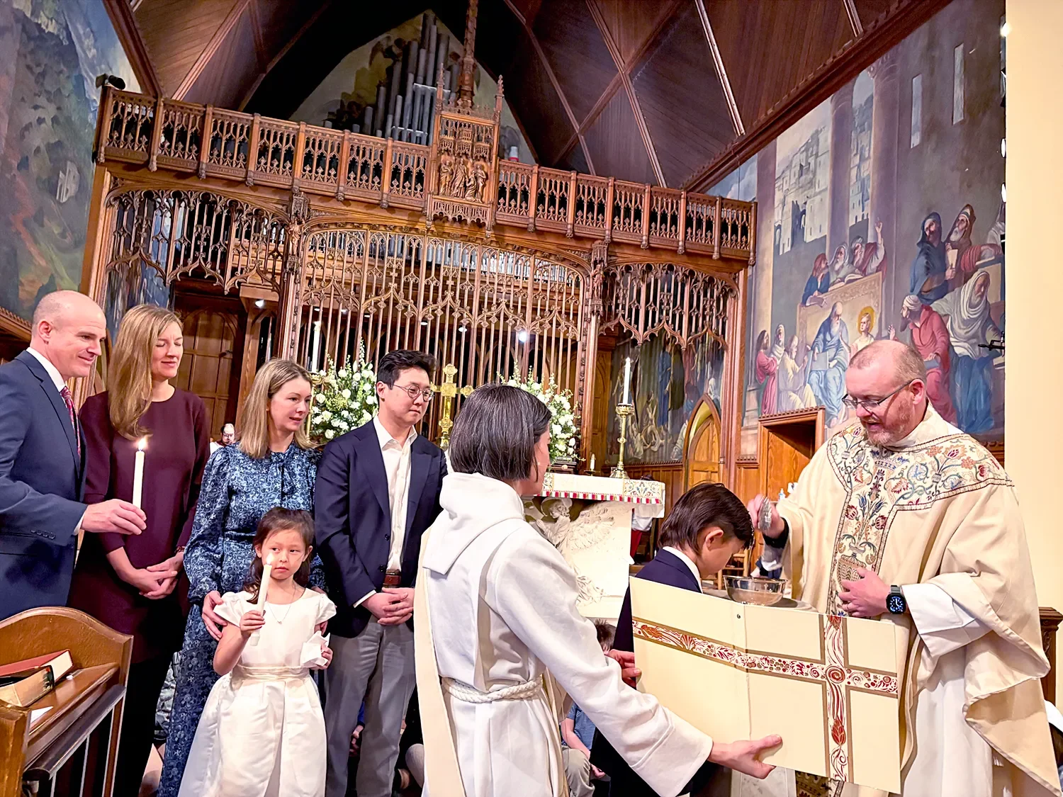 Father Dave baptizing a boy with his family standing with him at St. Thomas’ Church Whitemarsh.
