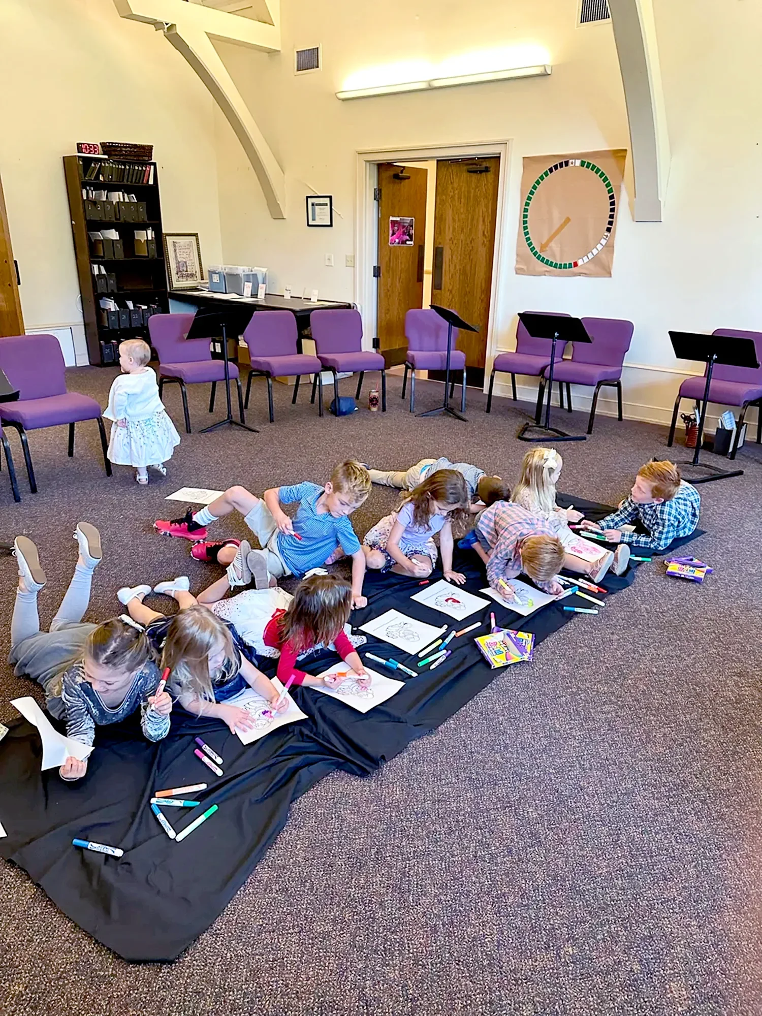 Children lying on the floor coloring on paper at St. Thomas’ Church Whitemarsh.