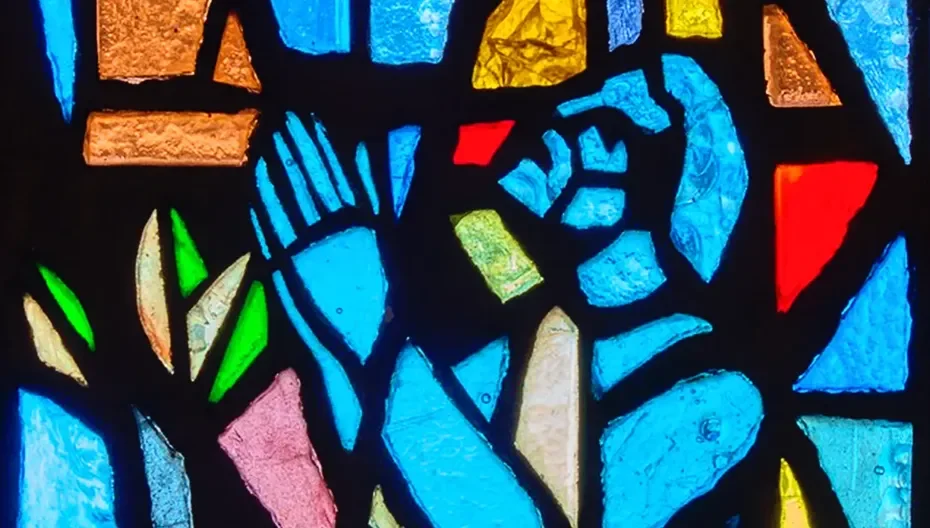 Stained‑glass depiction of a man praying inside the main church at St. Thomas’ Church Whitemarsh.