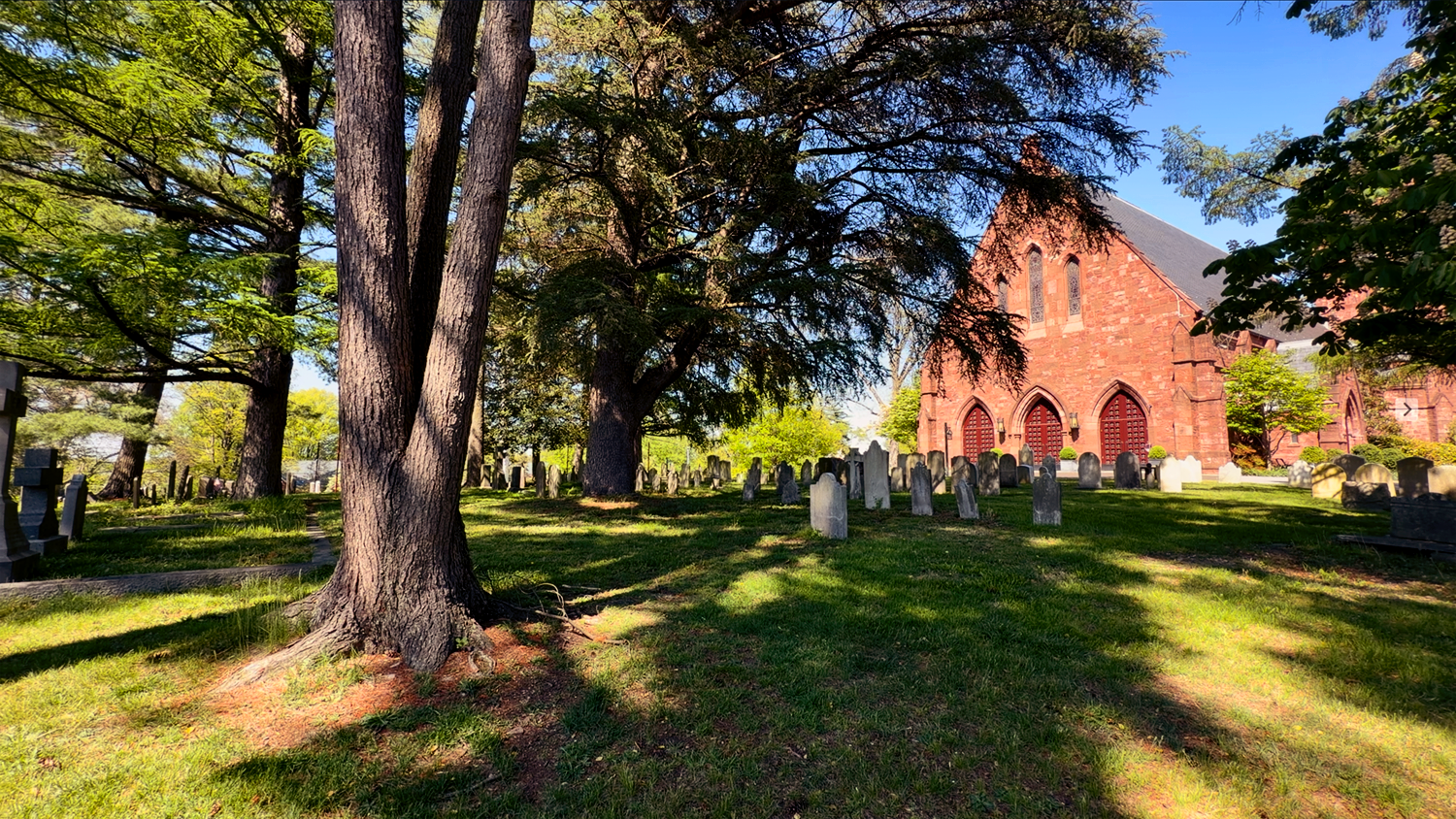 Peaceful tree-shaded historic cemetery with main church in the background at St. Thomas’ Church Whitemarsh.