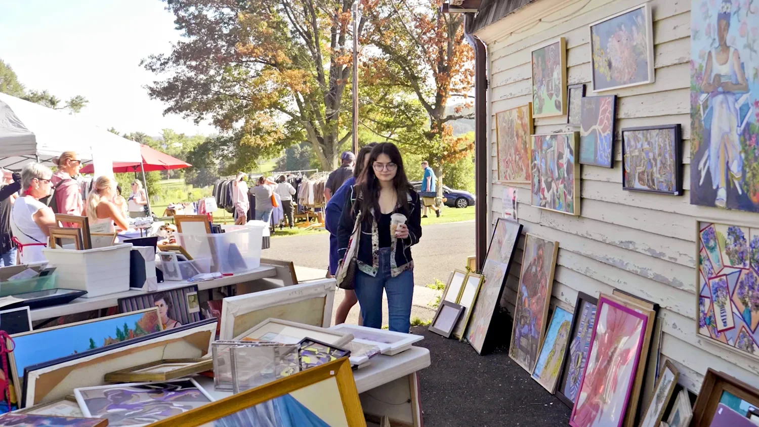 A young woman looking through artwork for sale at The Barn at St. Thomas’ Church Whitemarsh.