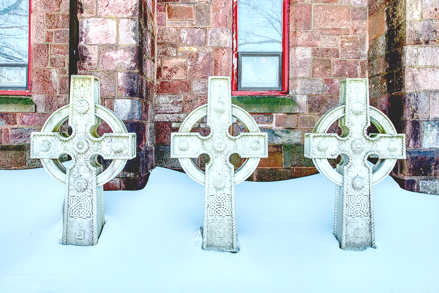 Three carved cross headstones in the snow at St. Thomas’ Church Whitemarsh.