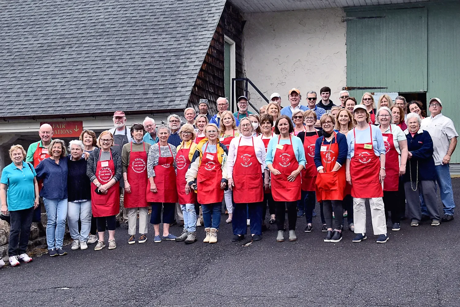 The Barn's team wearing red aprons and standing outside the barn at St. Thomas’ Church Whitemarsh.