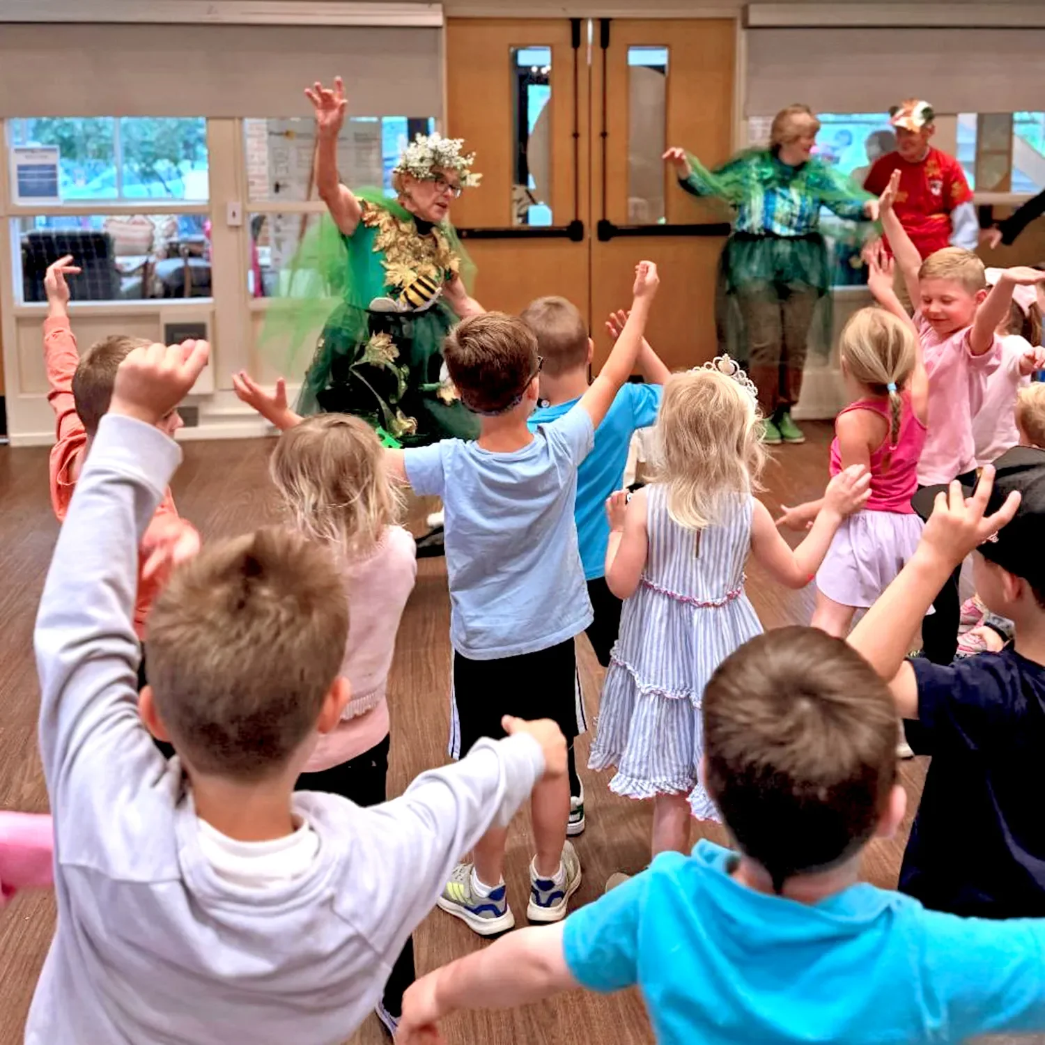 Children raising their arms while an adult in fairy costume leads an activity at St. Thomas’ Preschool.