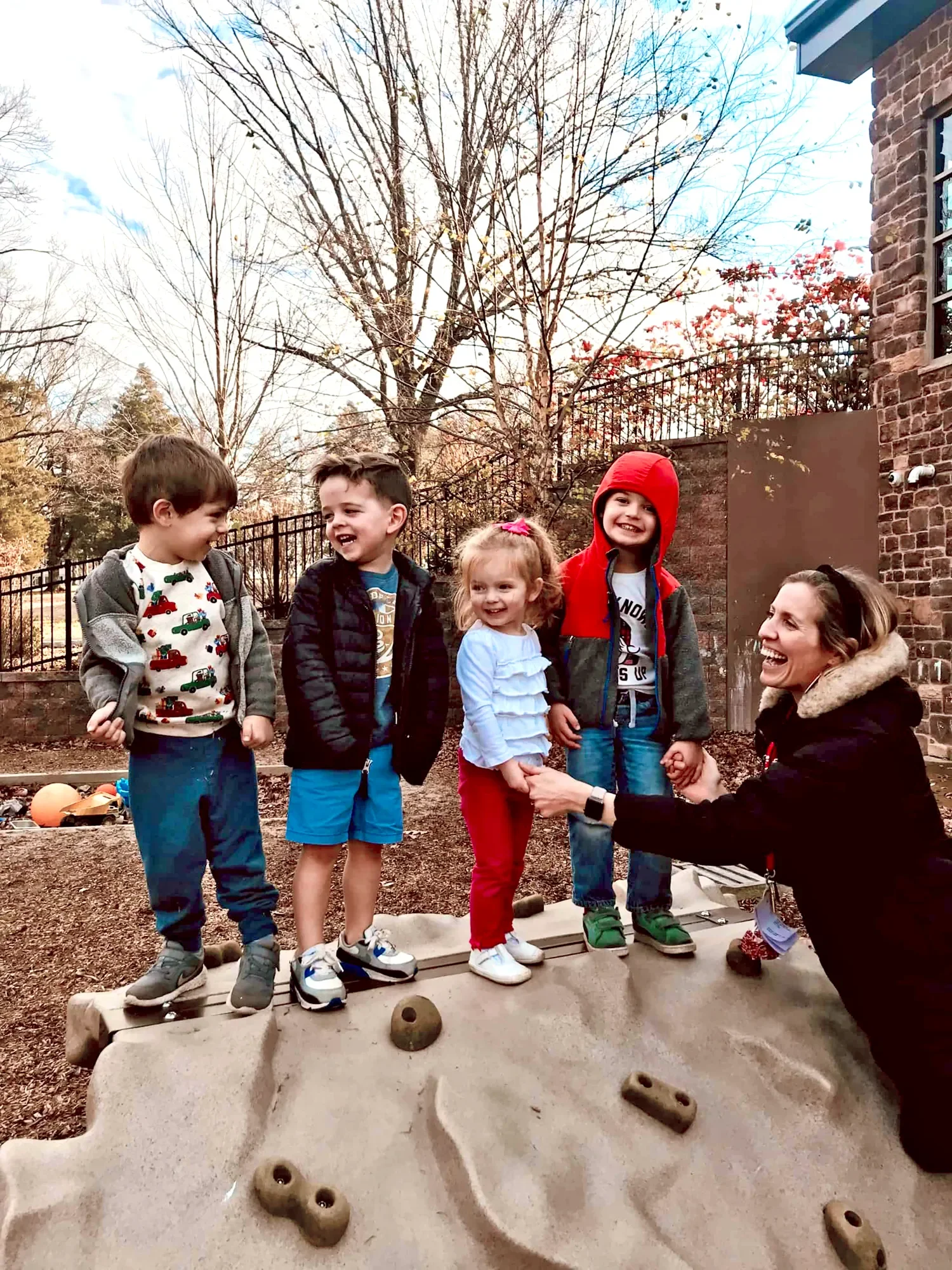 Four children and a teacher playing outside at St. Thomas’  Preschool.