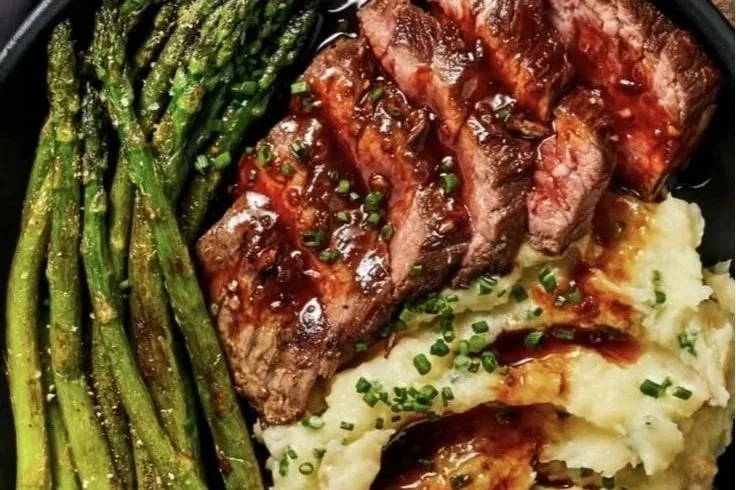 Home-cooked meal served at hunting camp with steak, mashed potatoes, and grilled asparagus.