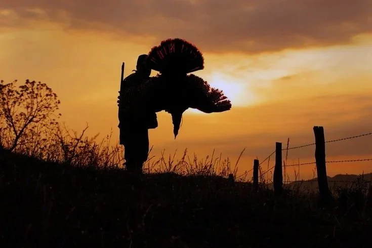 Hunter holding a harvested turkey at sunset during a guided hunting trip with legacy plains outfitters.