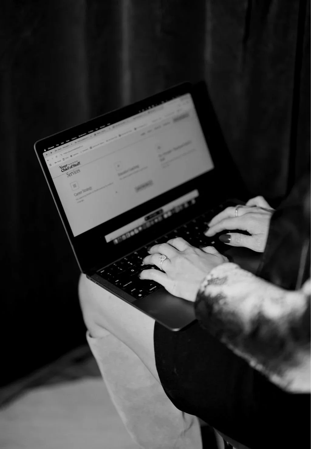 A person typing on a laptop, with a blurred document open on the screen.