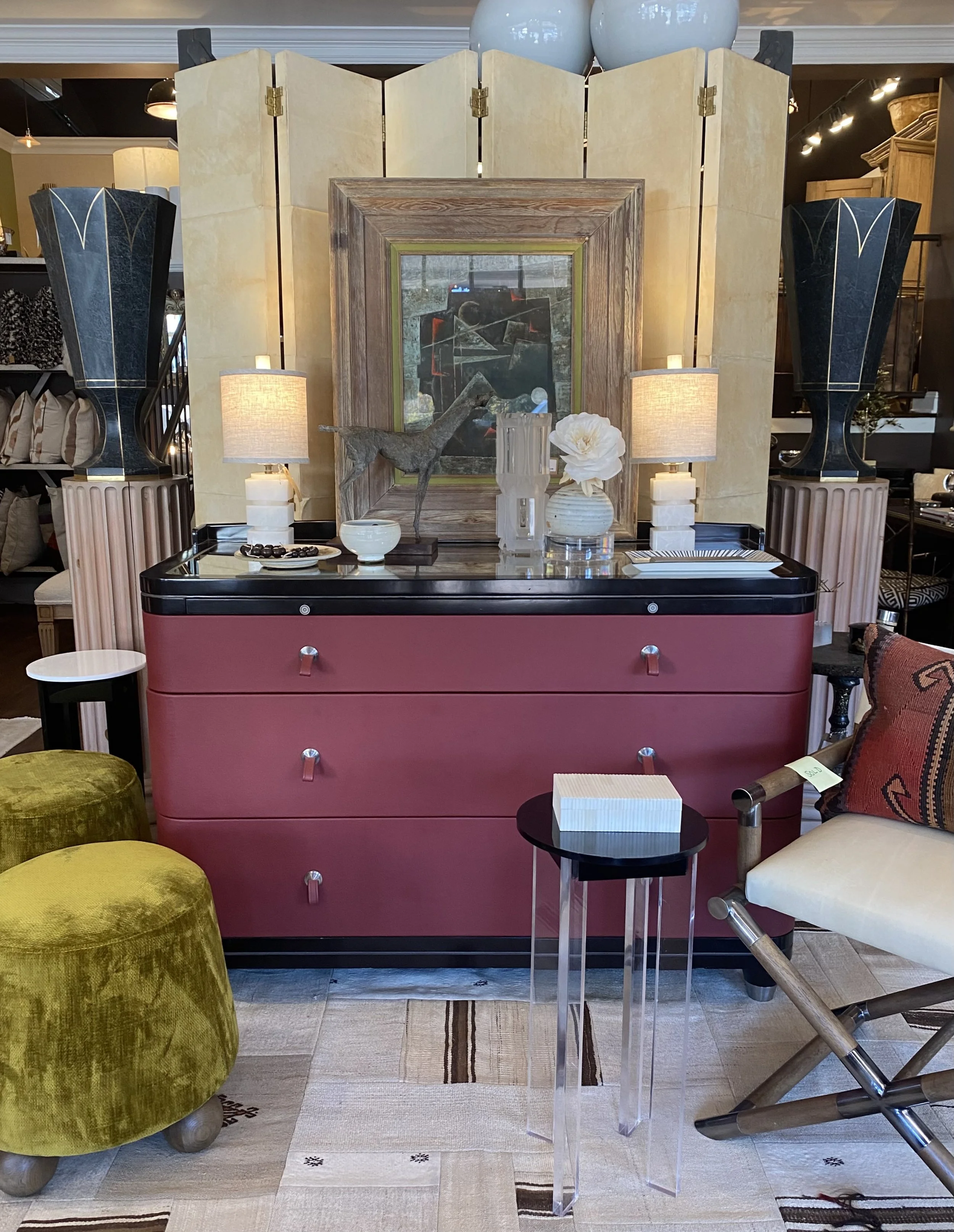 Display of home decor items including a framed painting, vases, a sculpture of a deer, lamps, and various tables and chairs in a furniture store.