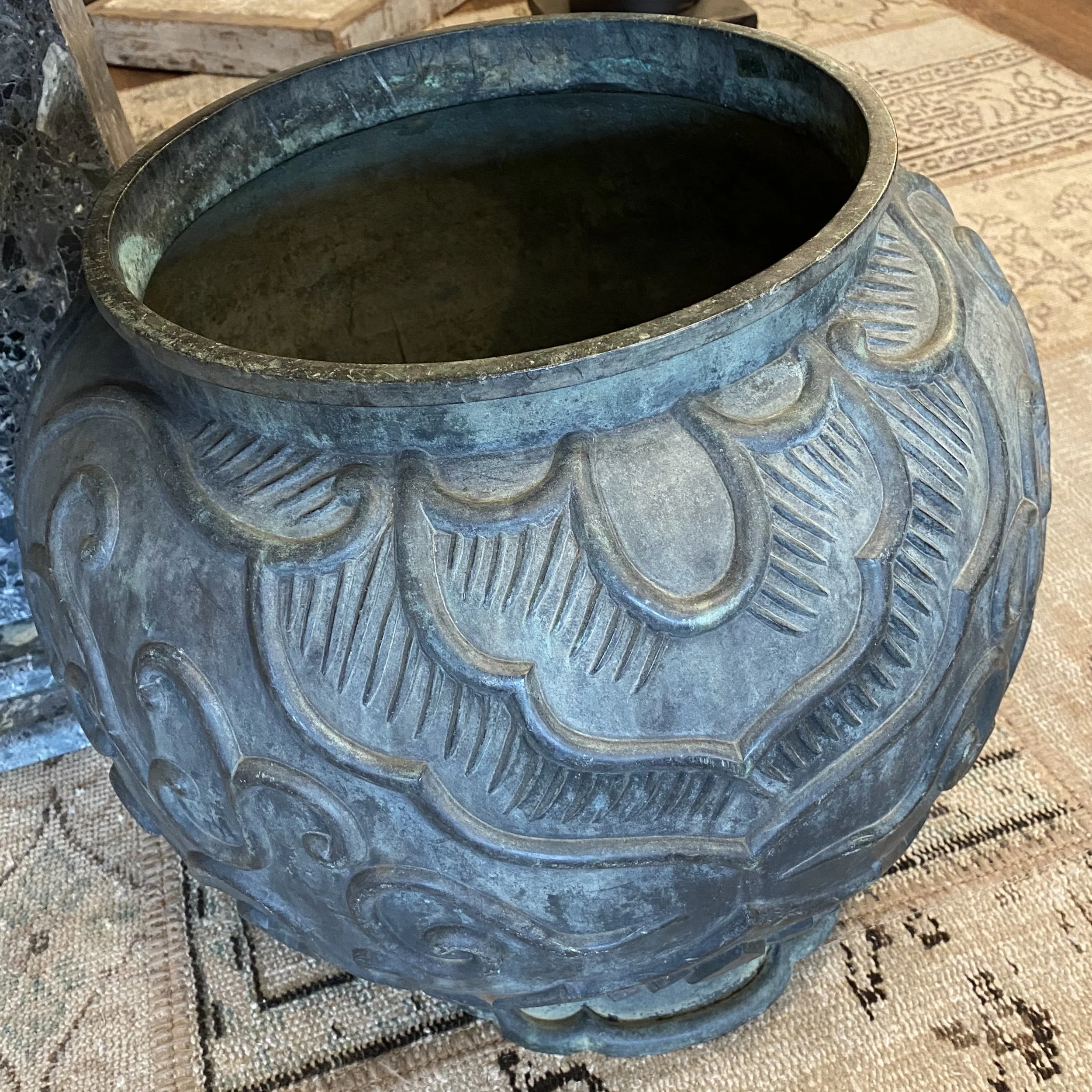 A decorative ceramic vase with carved leaf patterns, placed on a patterned fabric surface.