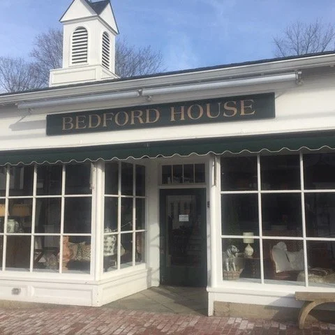 Facade of Bedford House with large windows and a black door, white trim, and a sign reading 'BEDFORD HOUSE' above the entrance.
