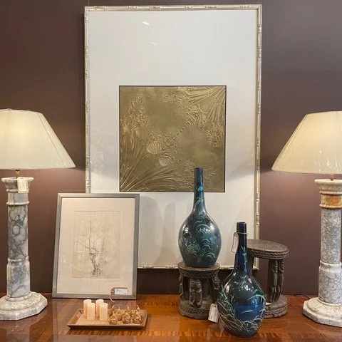Decorative table with framed art, vases, and lamps in a living room.