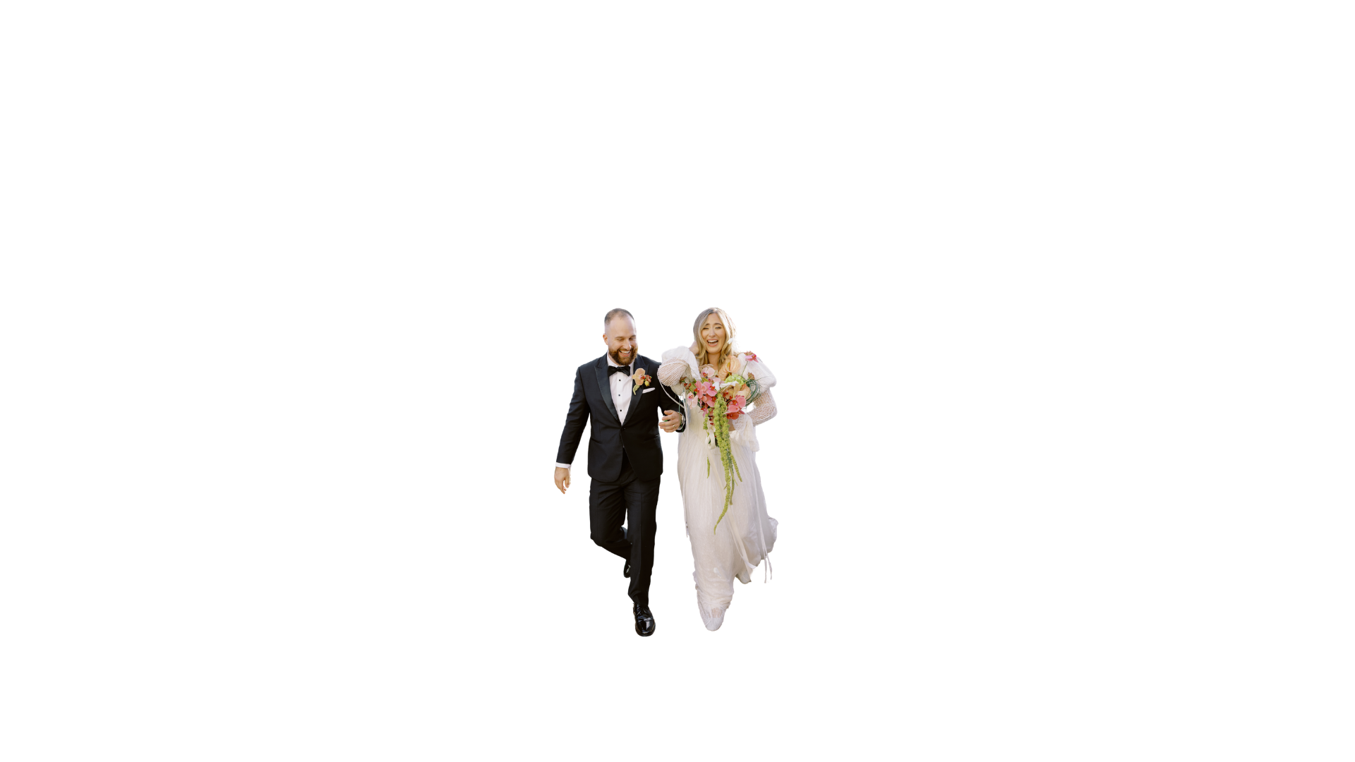 A bride and groom walking down the aisle, smiling, with the bride in a white wedding dress holding a bouquet and the groom in a black tuxedo with a bow tie.